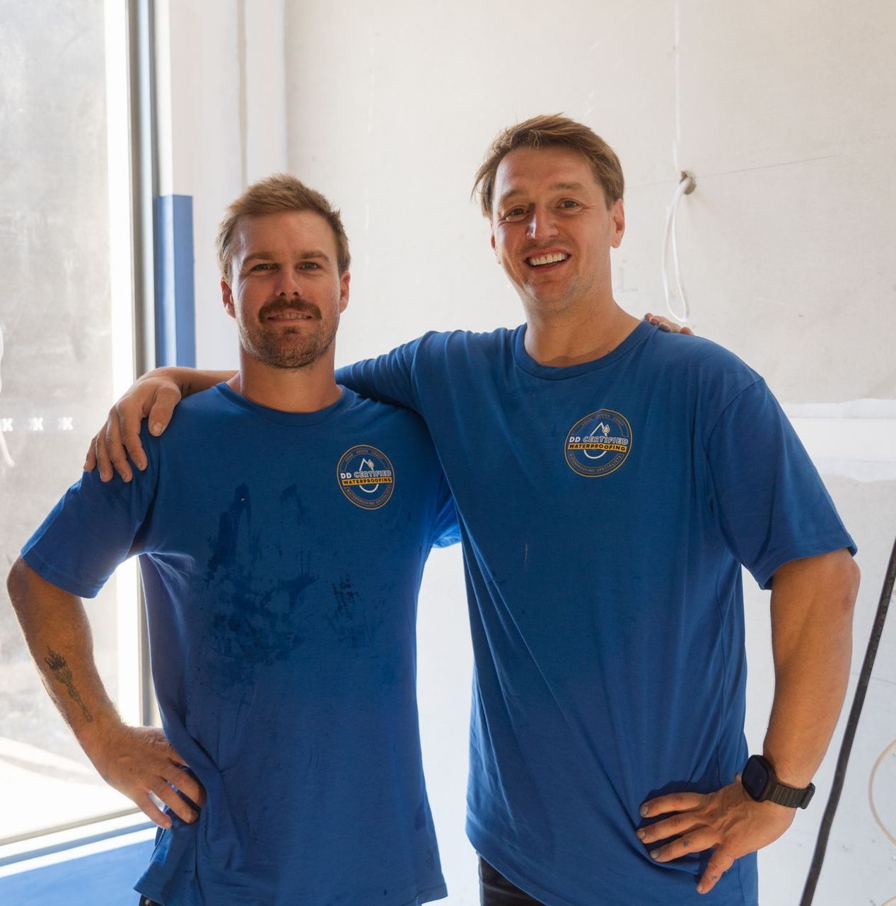 Two men are posing for a picture and one has a tattoo on his arm