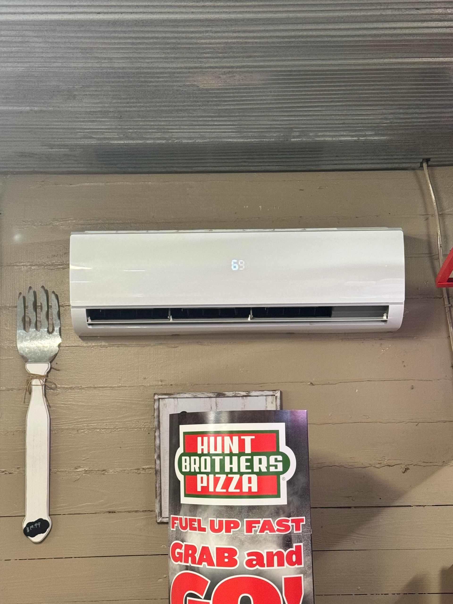 A fork is hanging on a wall next to a sign for hunt brothers pizza