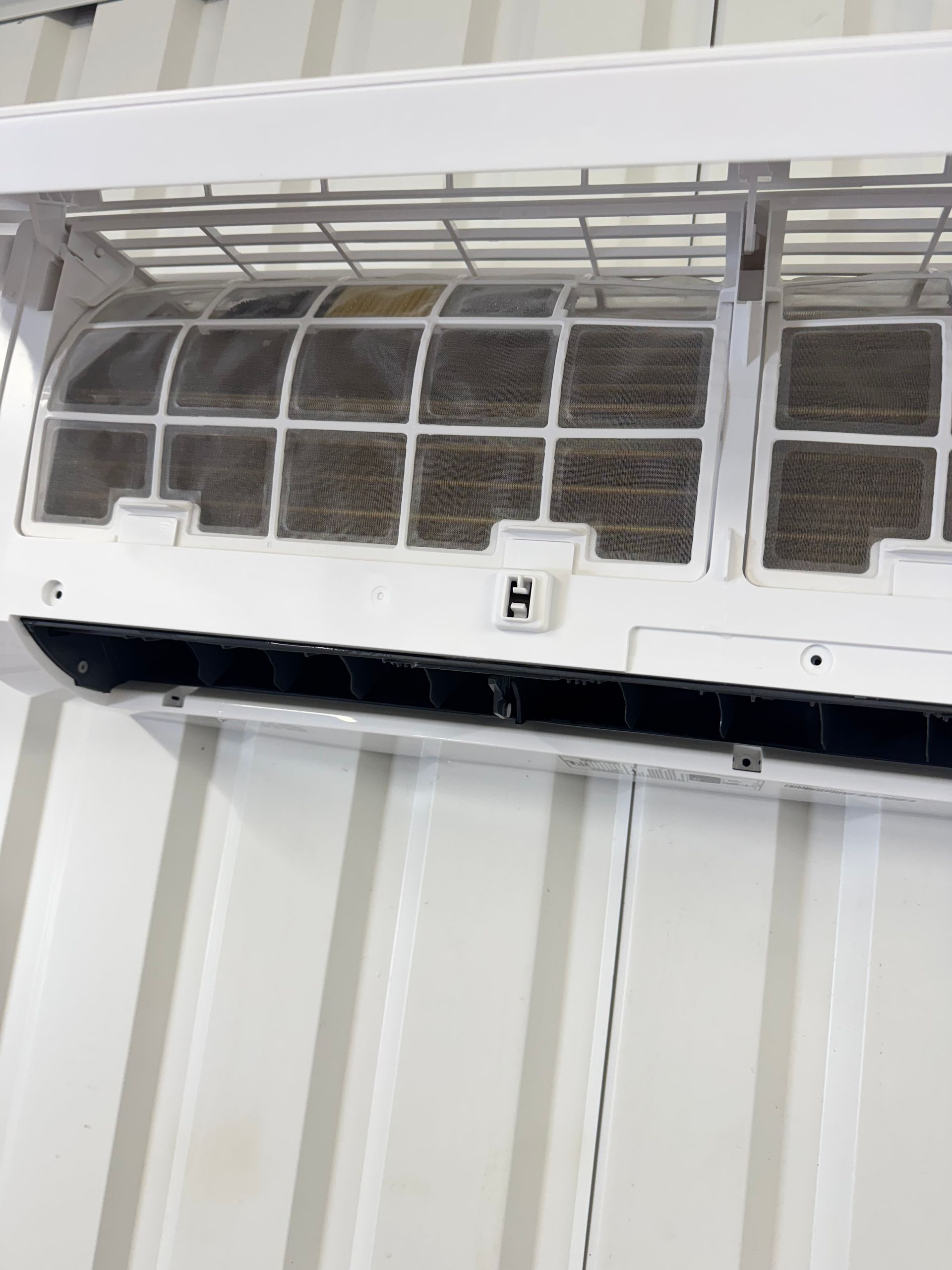 A white air conditioner is hanging on a white wall.