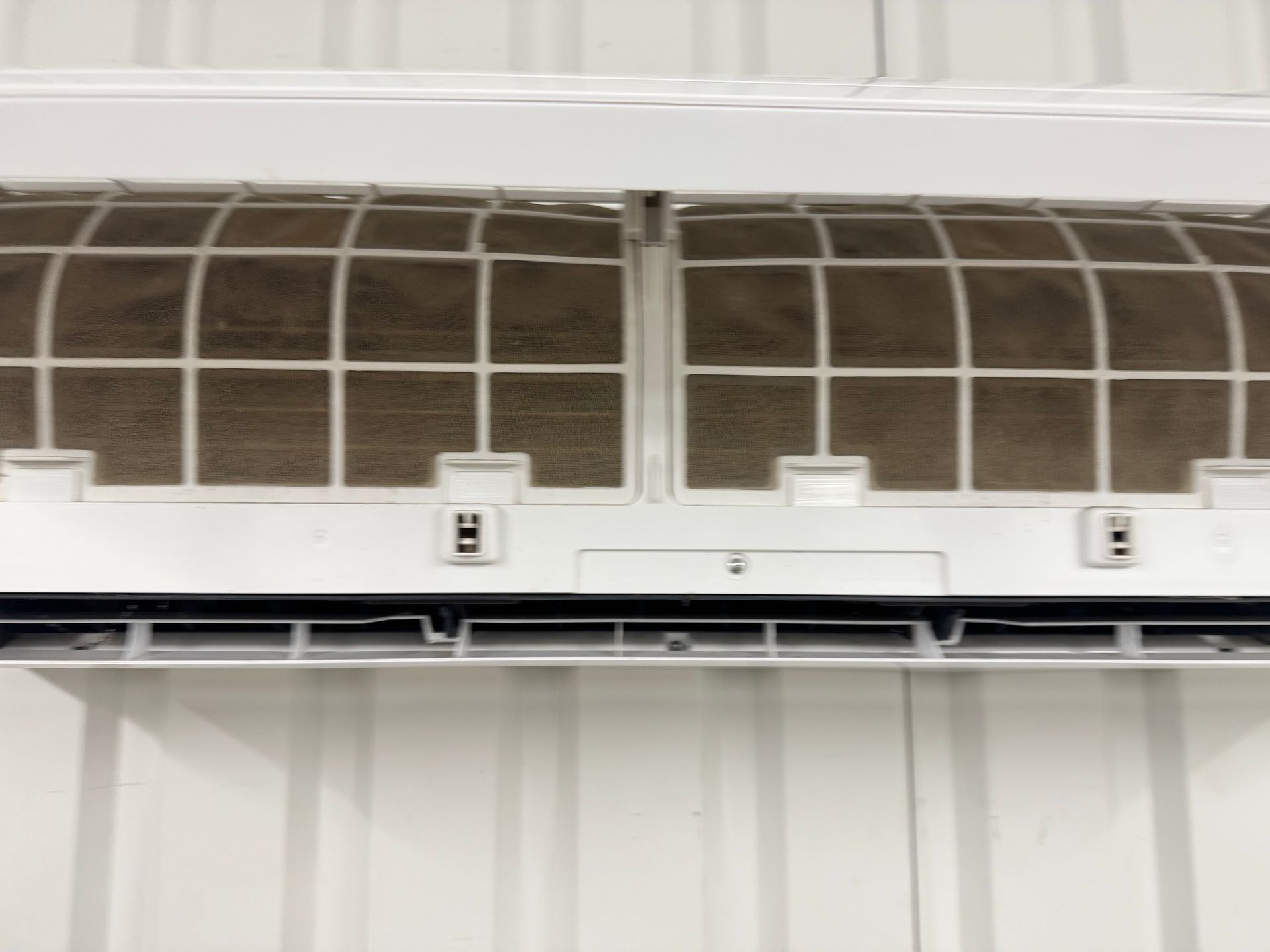 A white air conditioner is hanging on a white wall