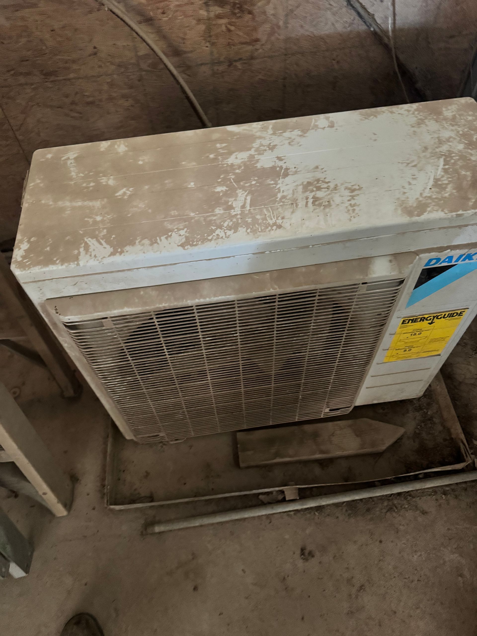 A dirty air conditioner is sitting on the floor.