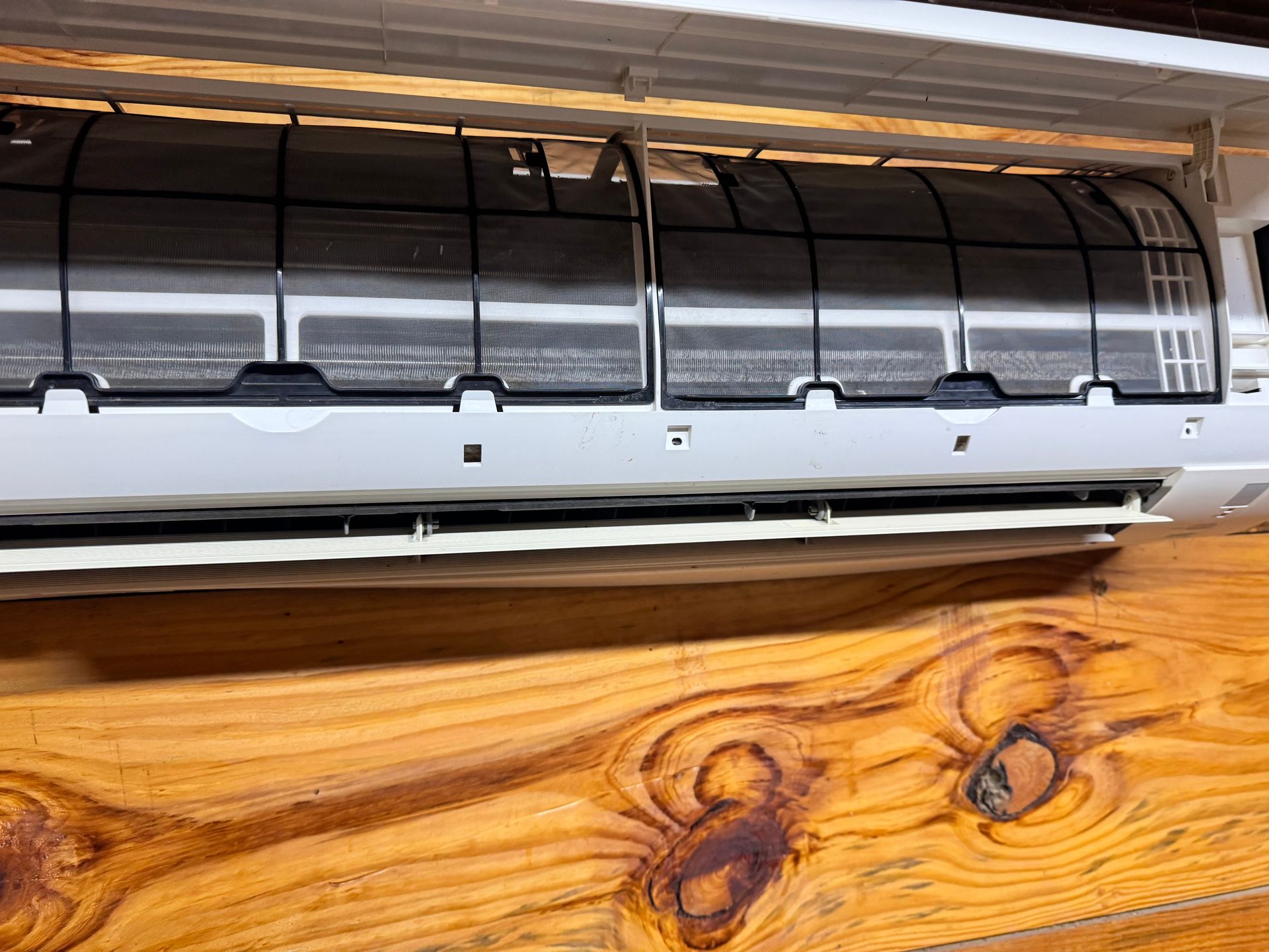 A white air conditioner is hanging on a wooden wall.