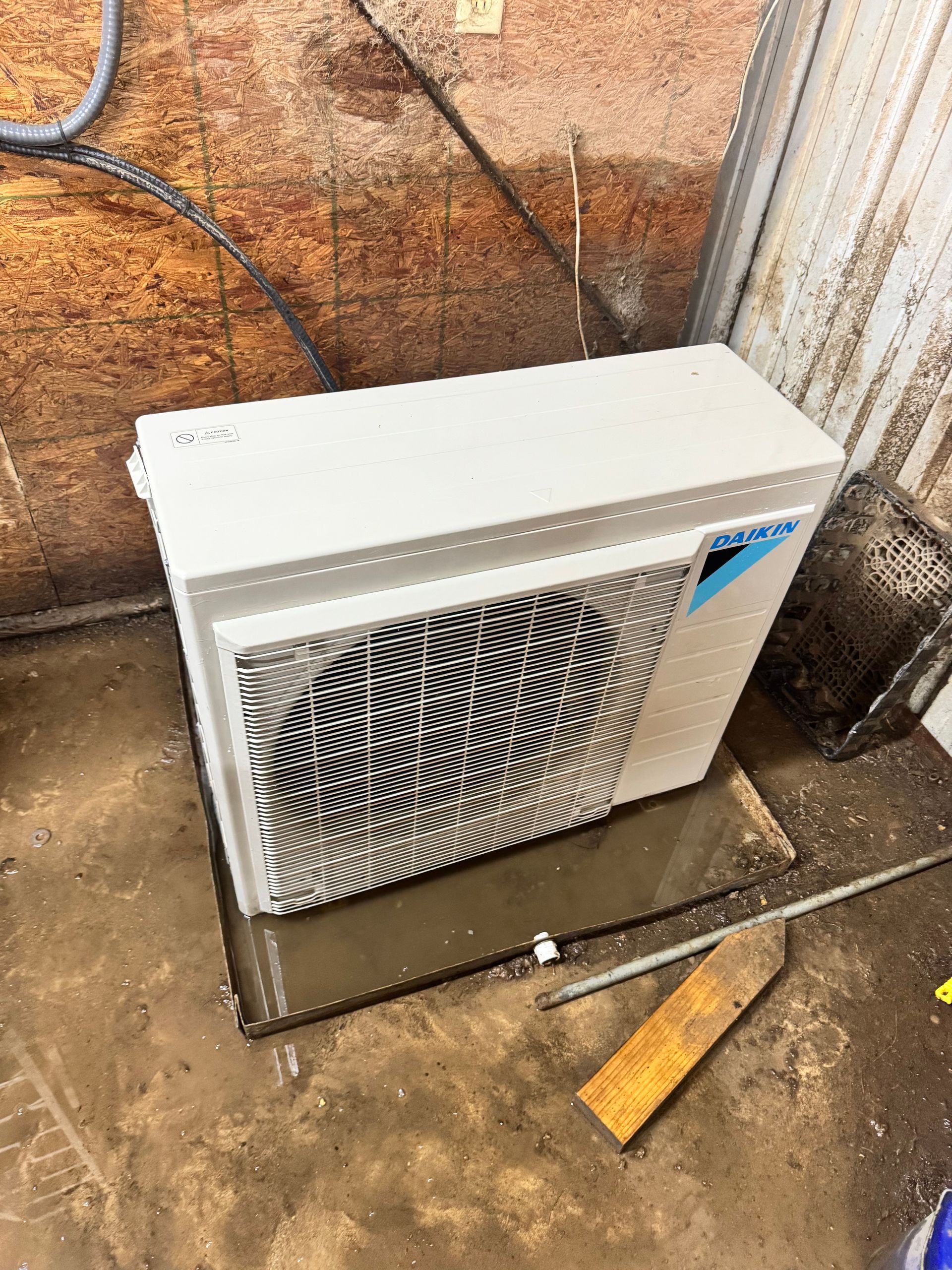 A white air conditioner is sitting on the ground in a room.