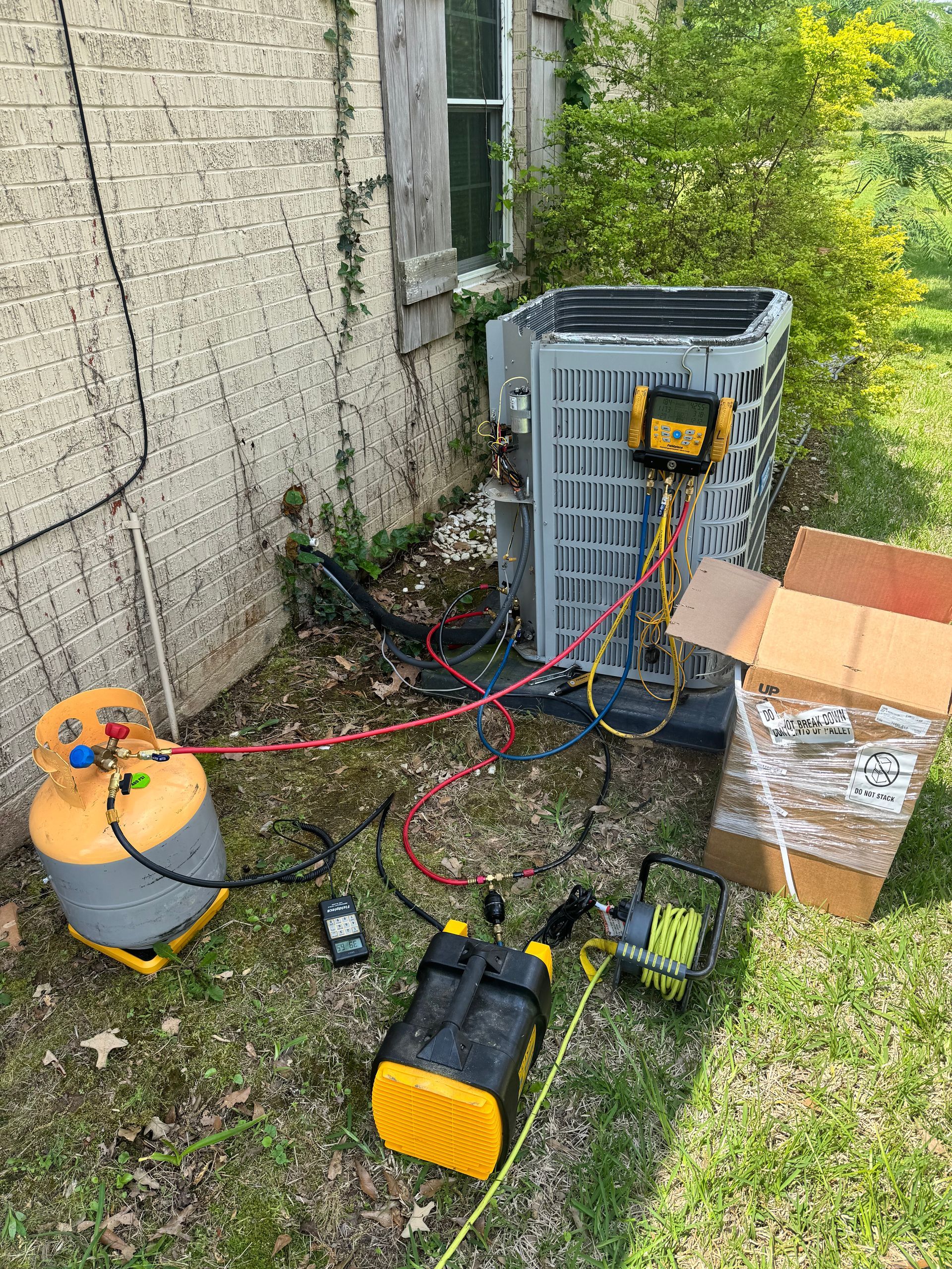 An air conditioner is being repaired in the backyard of a house.