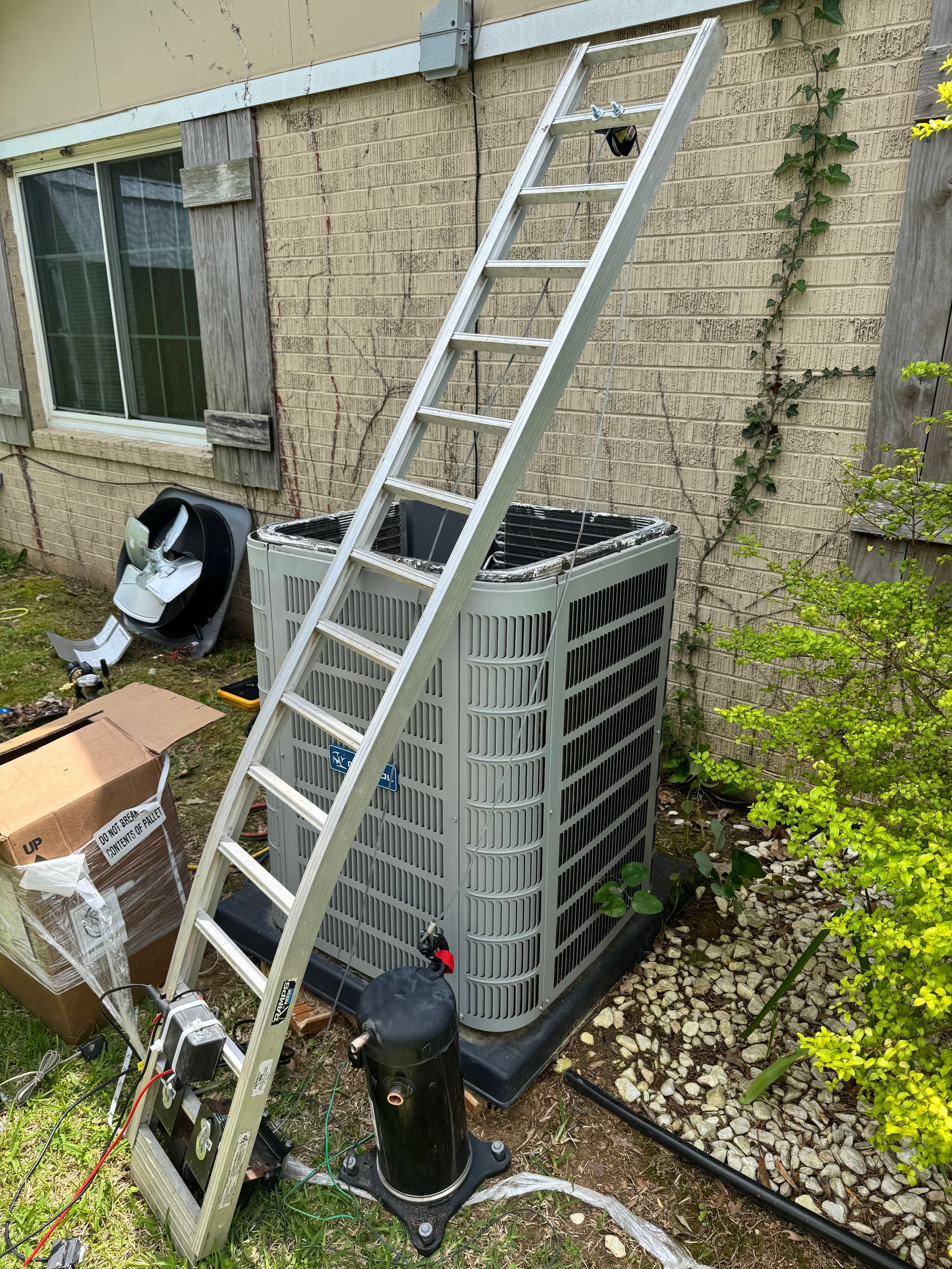 A ladder is sitting on top of an air conditioner outside of a house.