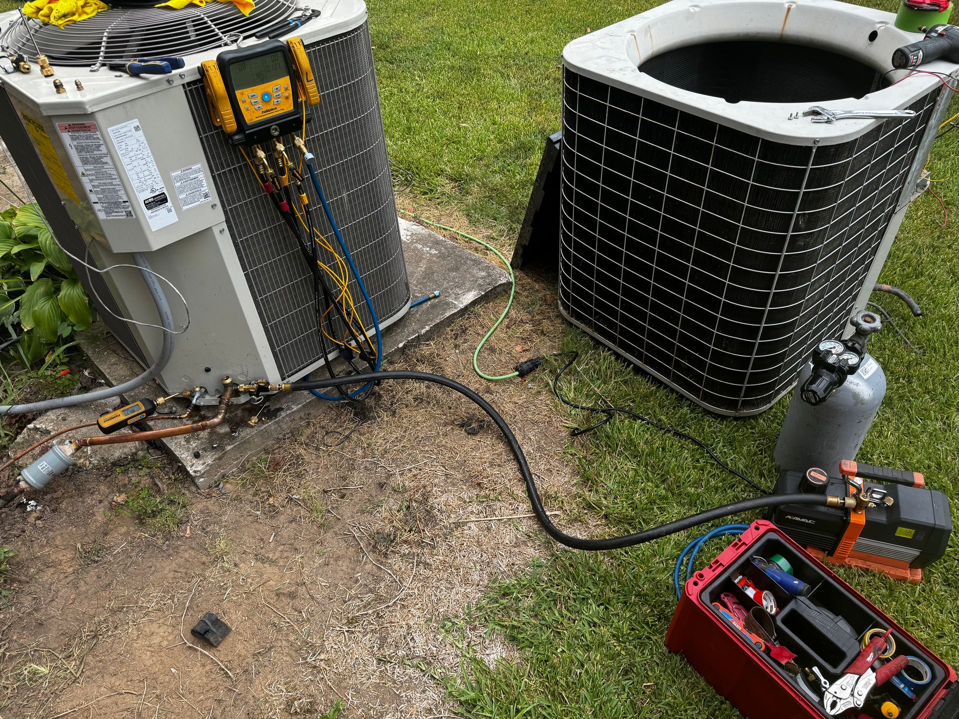 A couple of air conditioners sitting on top of a lush green field.