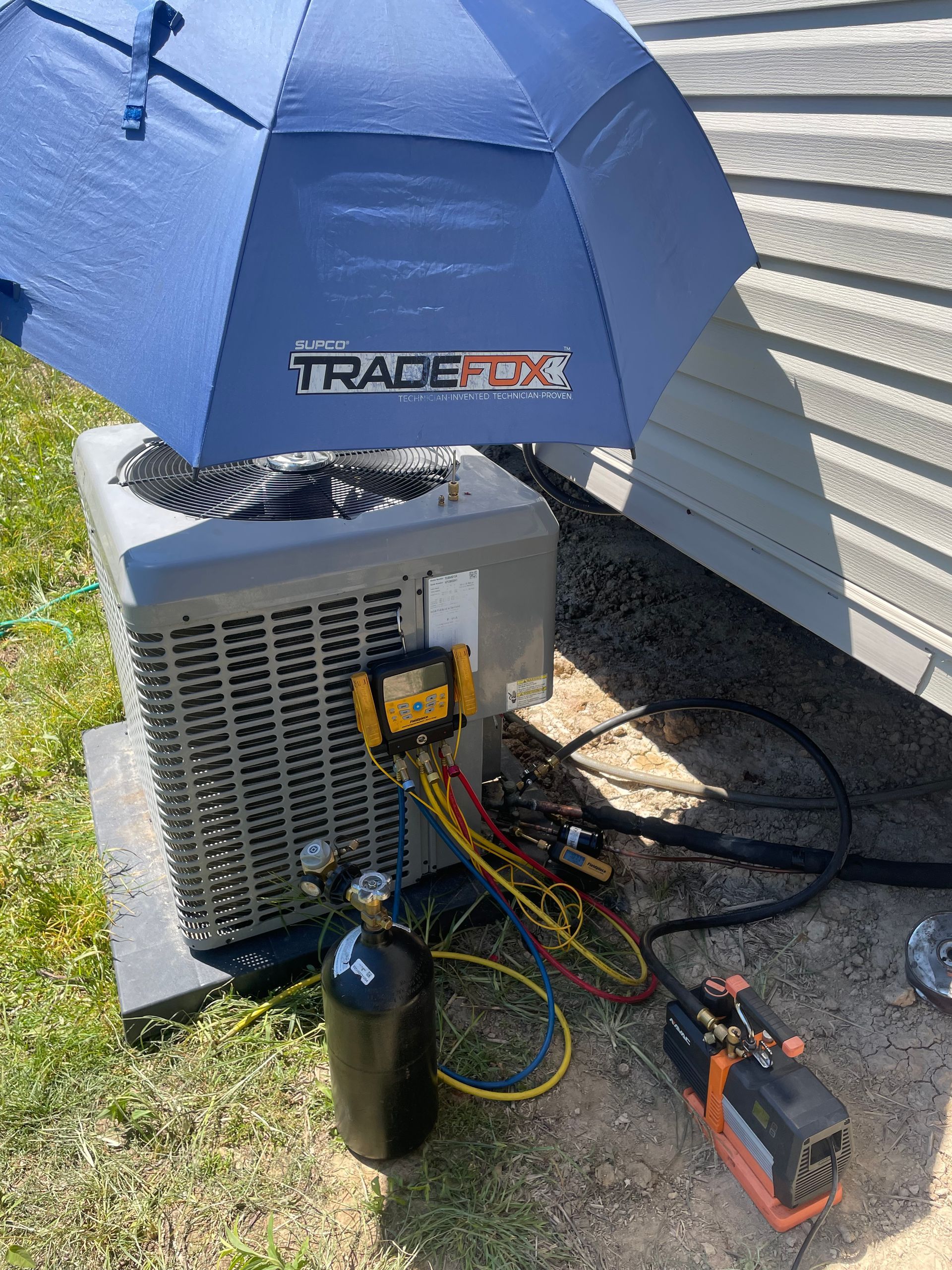 A blue umbrella is sitting on top of an air conditioner.