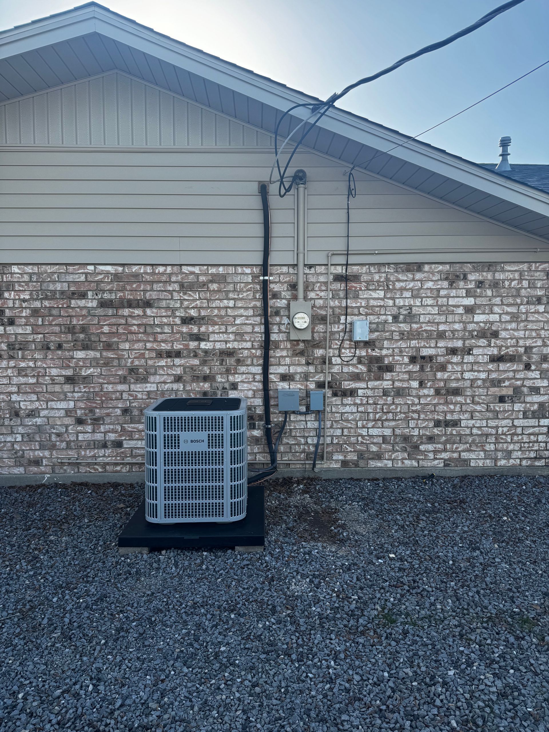 An air conditioner is installed on the side of a brick house.
