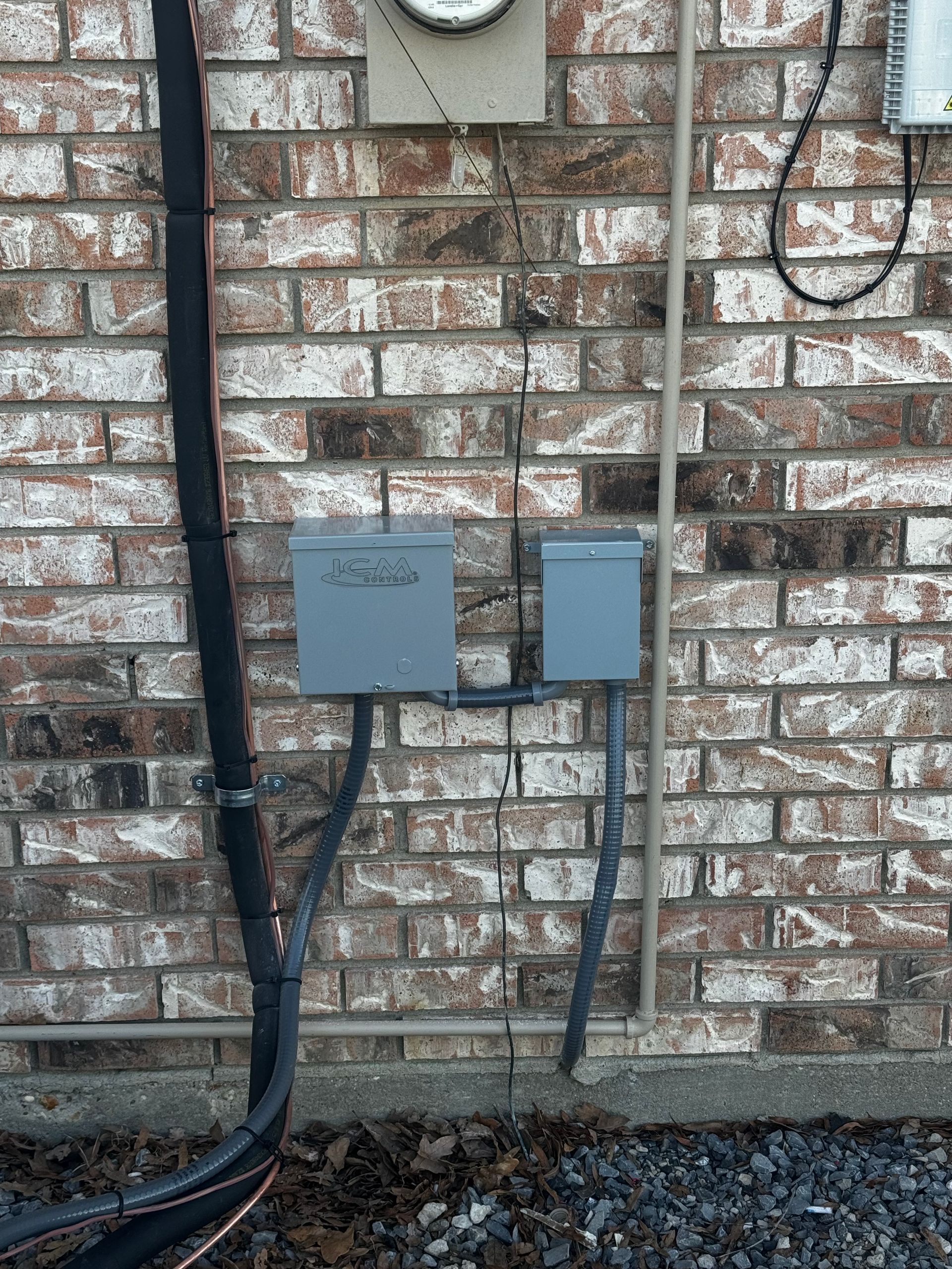 A brick wall with a box and wires attached to it.