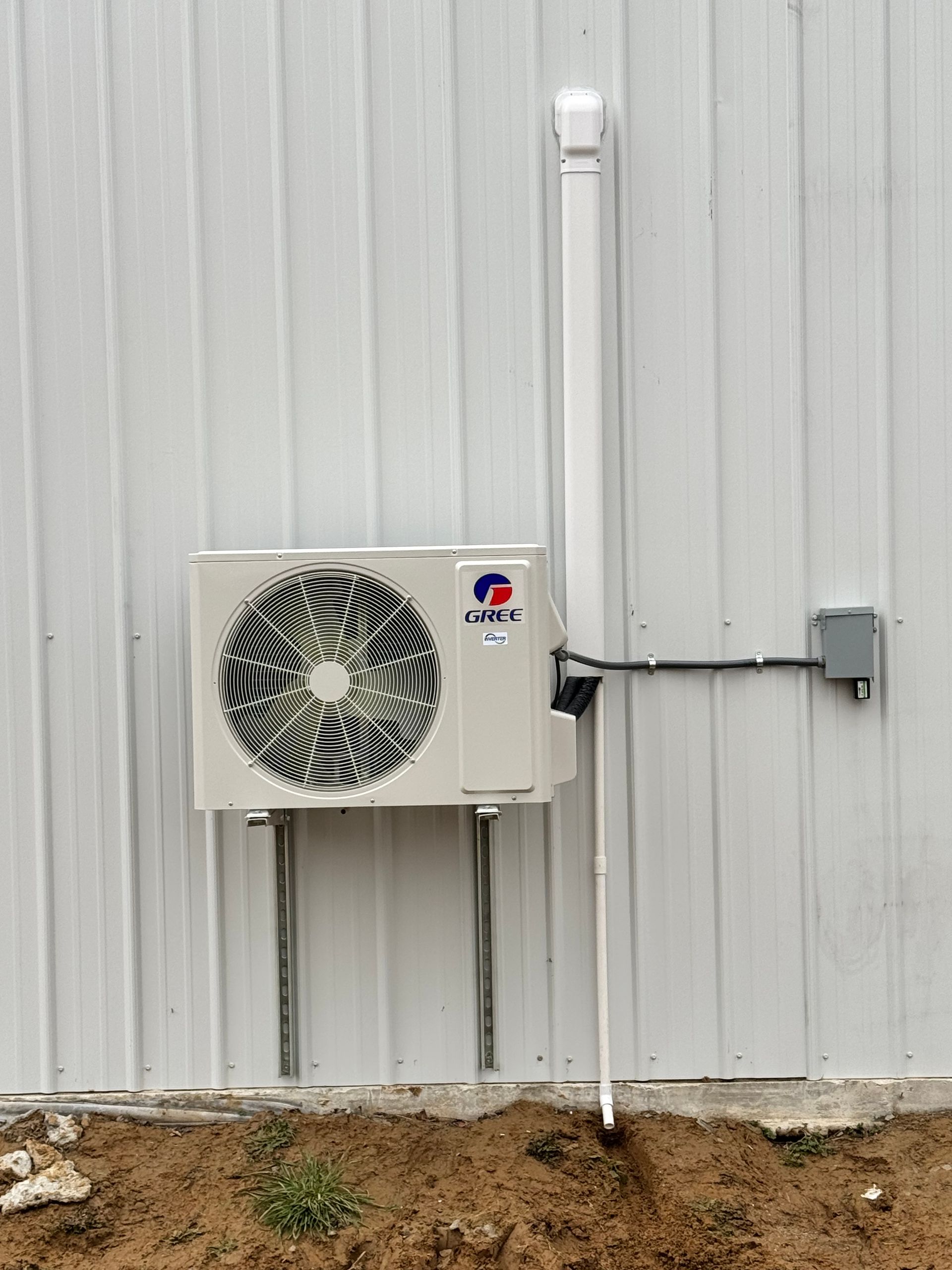 A white air conditioner is mounted on the side of a building.