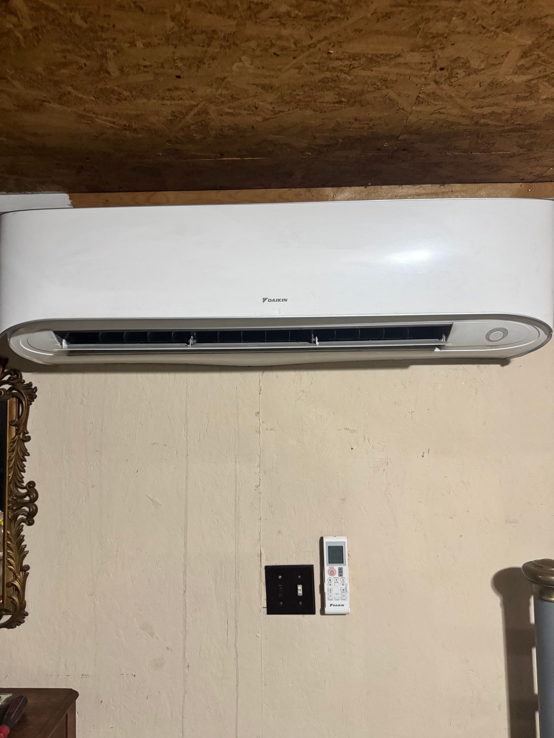 A white air conditioner is mounted on a wall next to a remote control.