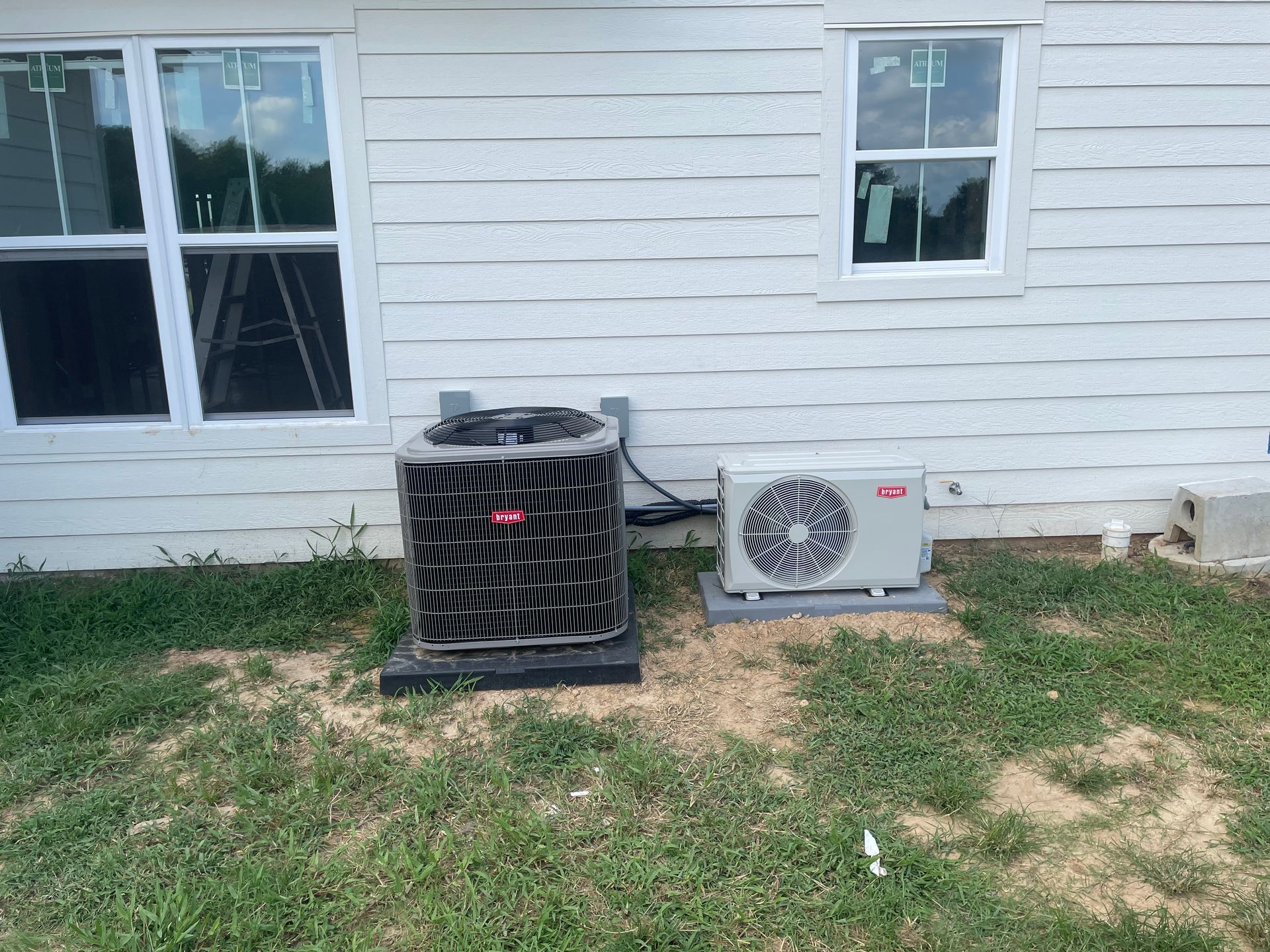 An air conditioner is sitting on the side of a house next to a window.