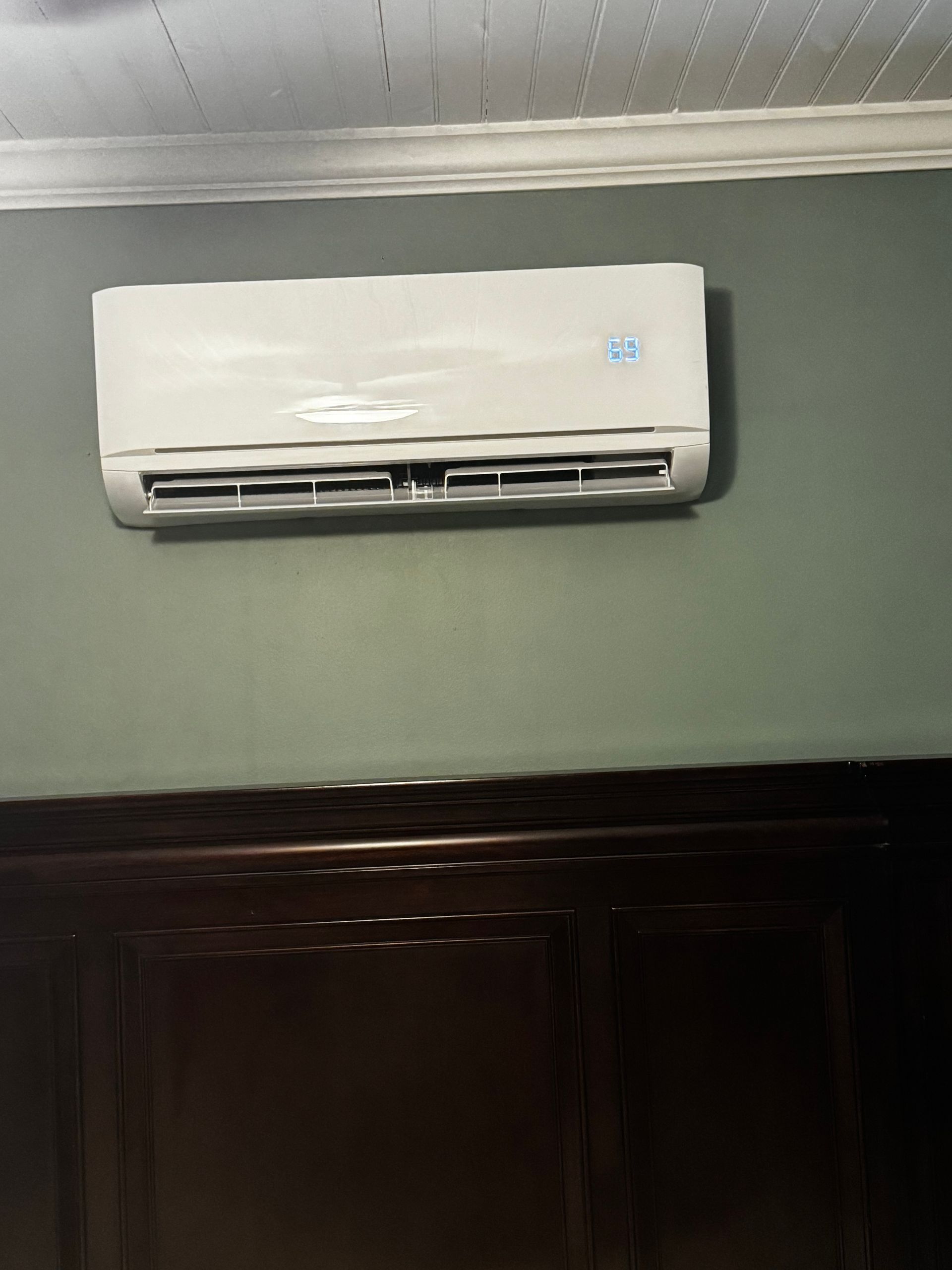 A white air conditioner is hanging on a wall in a room.