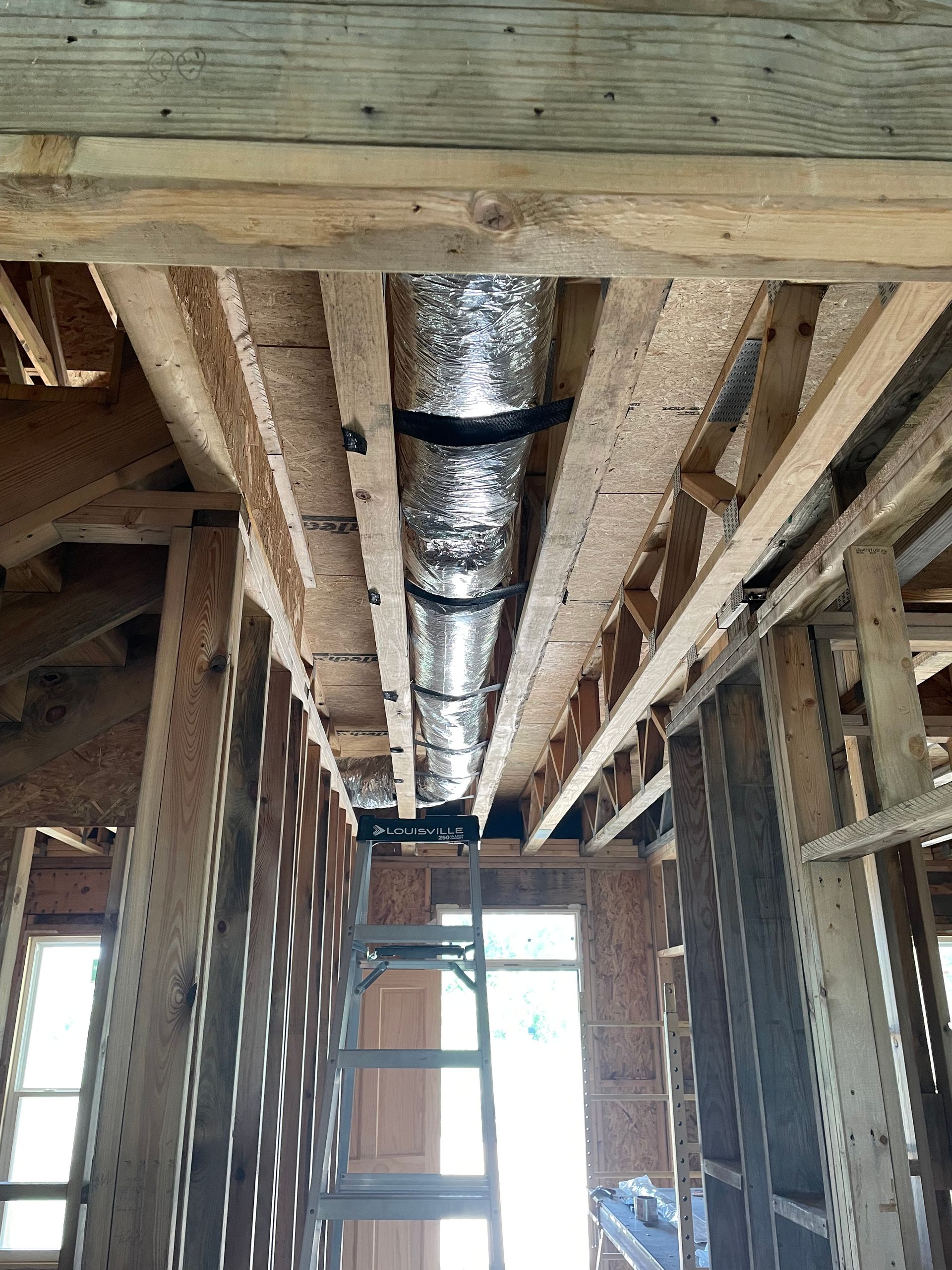 A ladder is hanging from the ceiling of a building under construction.