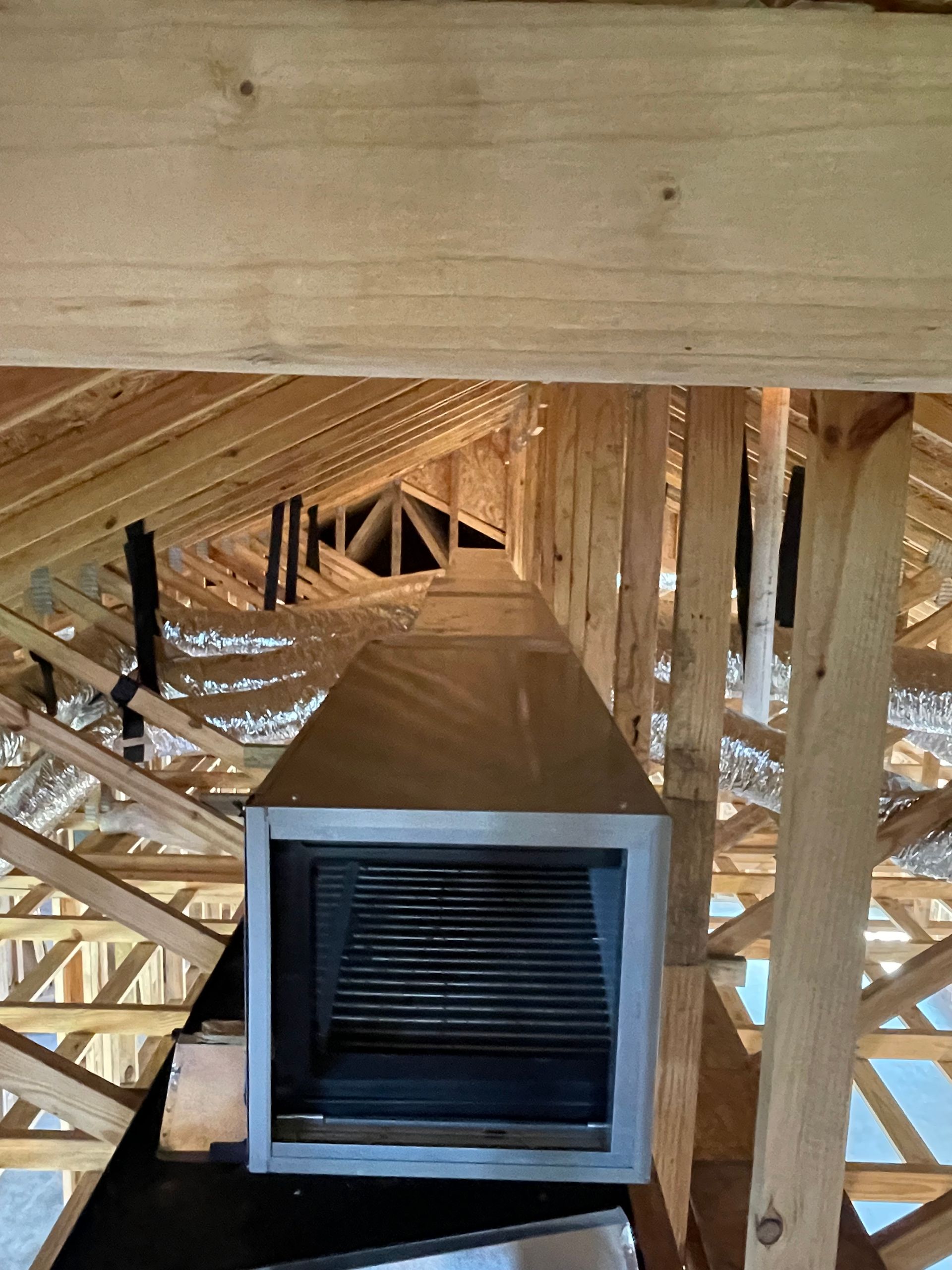 A ventilation system is being installed in the attic of a house under construction.