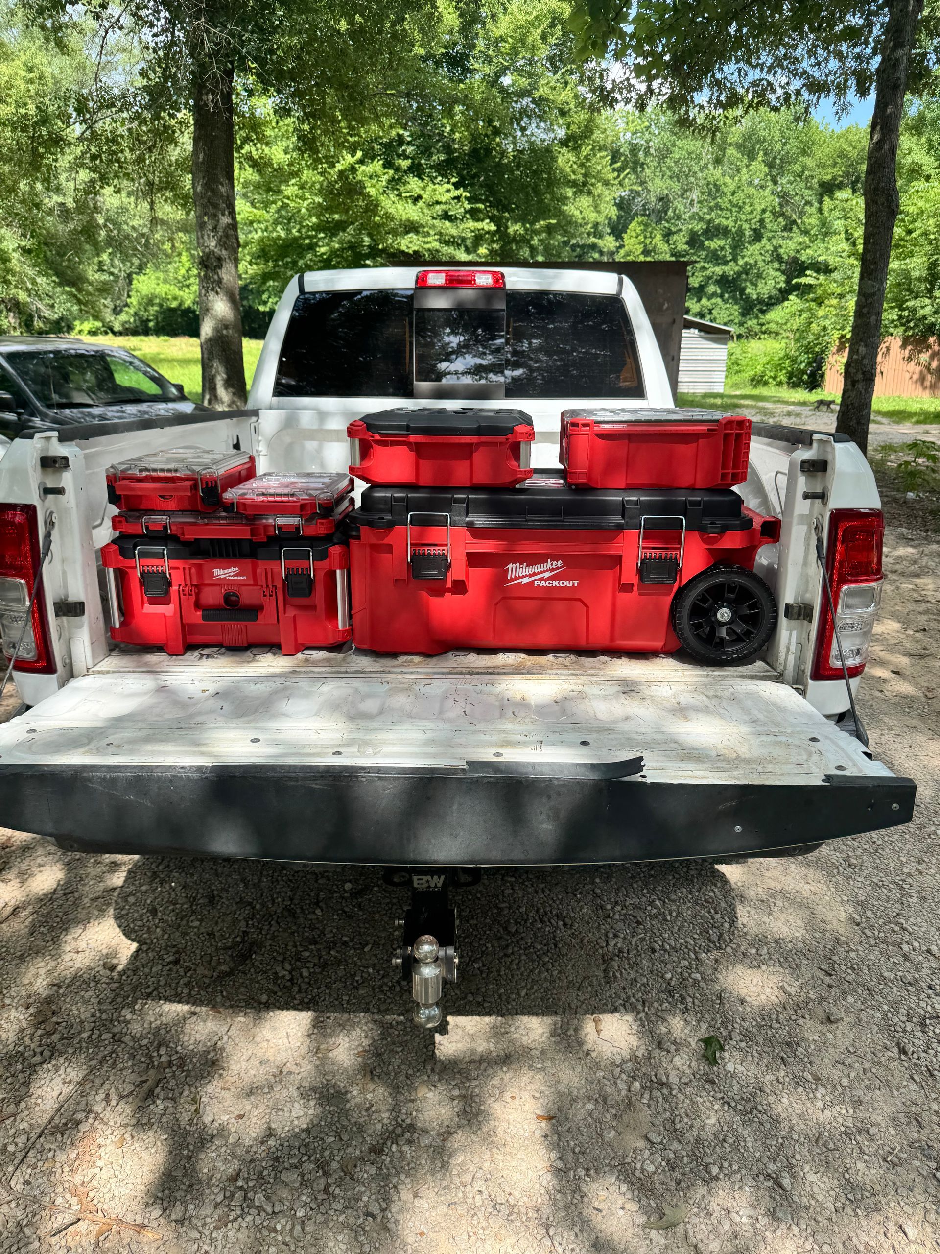 A white truck with a bunch of red tools in the back.