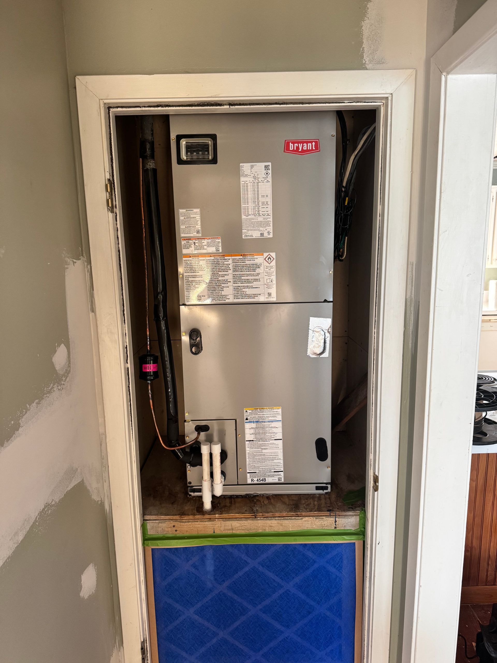 An air conditioner is sitting inside of a doorway in a room.