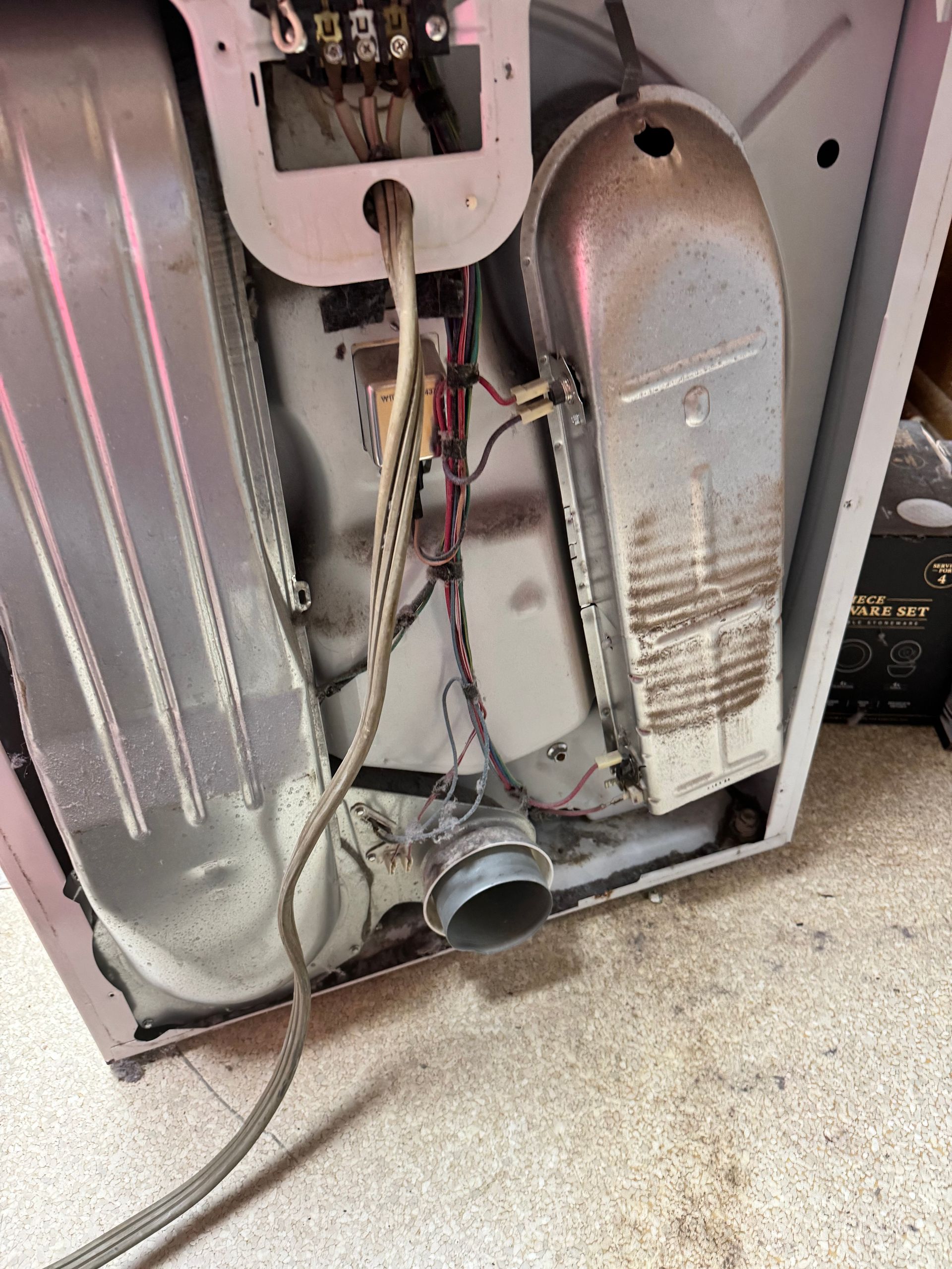 The back of a washing machine with a hose coming out of it.