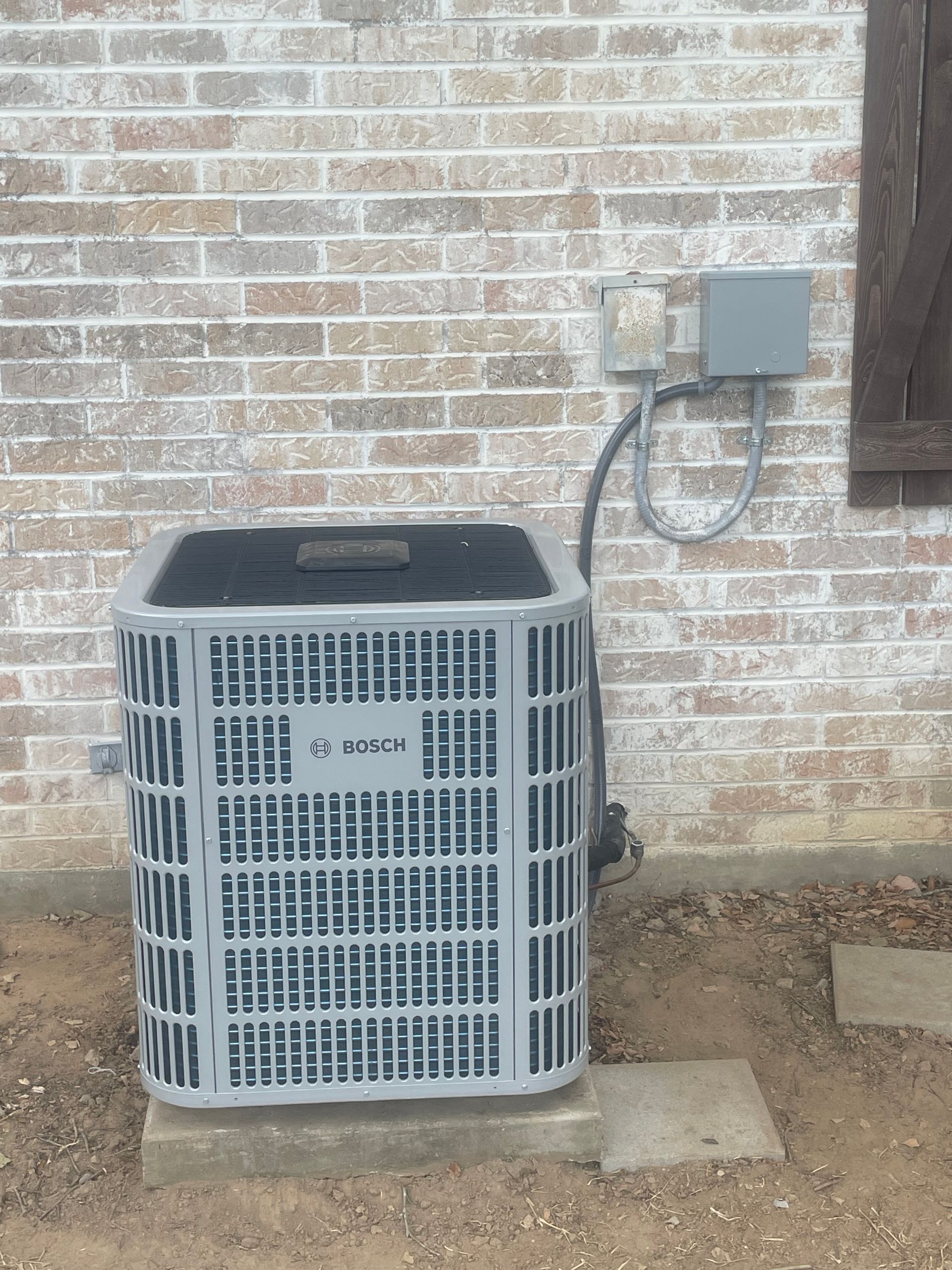 An air conditioner is sitting outside of a brick building.