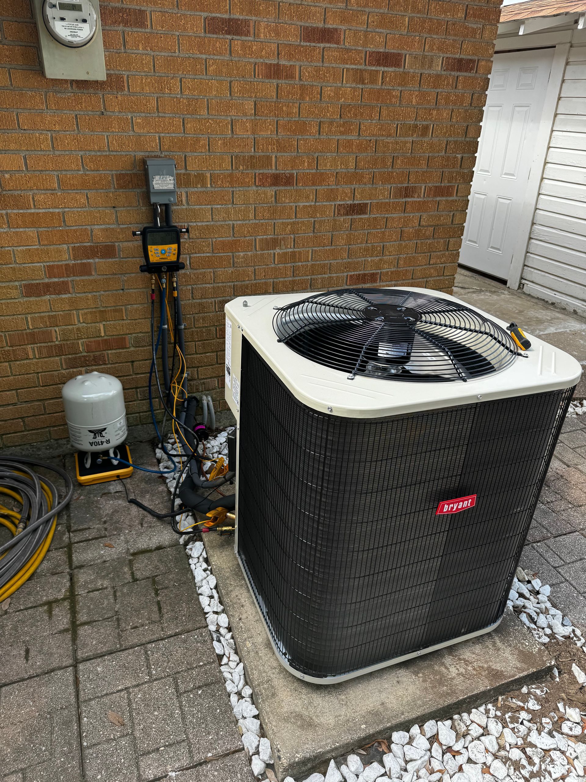 An air conditioner is sitting on the side of a brick building.