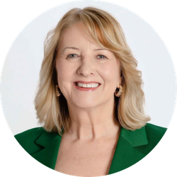 Woman with blonde hair, smiling, wearing a green blazer.