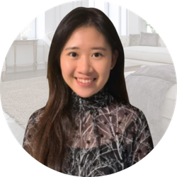 Smiling woman in a sheer black top; background is a blurry living room.