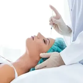 Practitioner administering facial injection to a reclining patient in a bright clinic