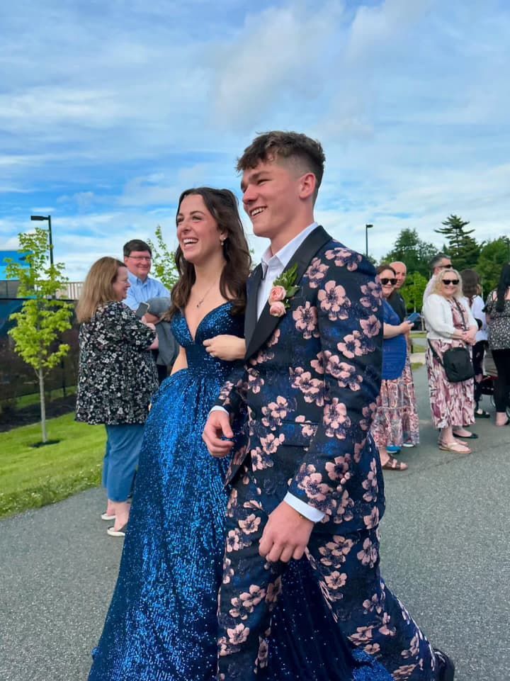 A man in a suit and a woman in a dress are walking down the street.