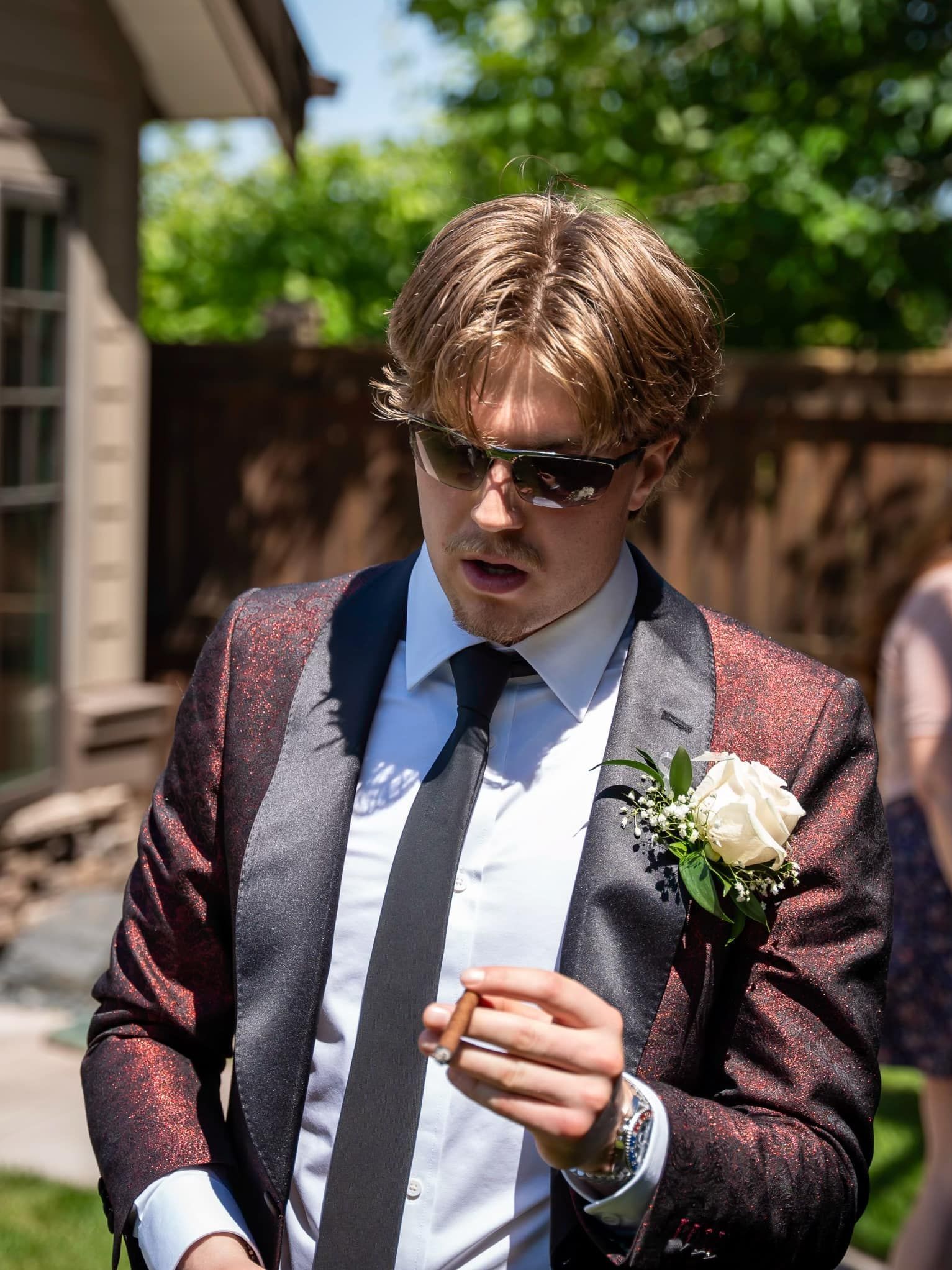 A man in a suit and tie is holding a flower in his pocket.