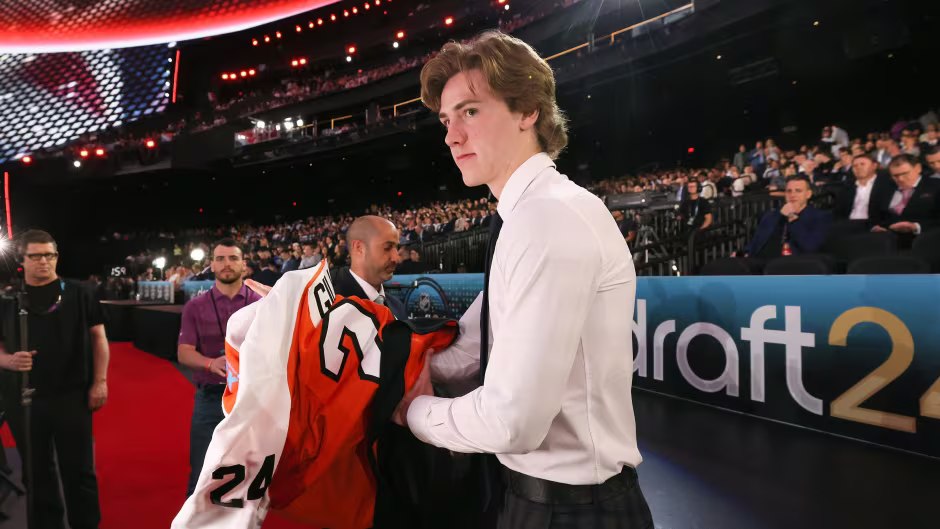A man is holding a jersey with the number 24 on it.