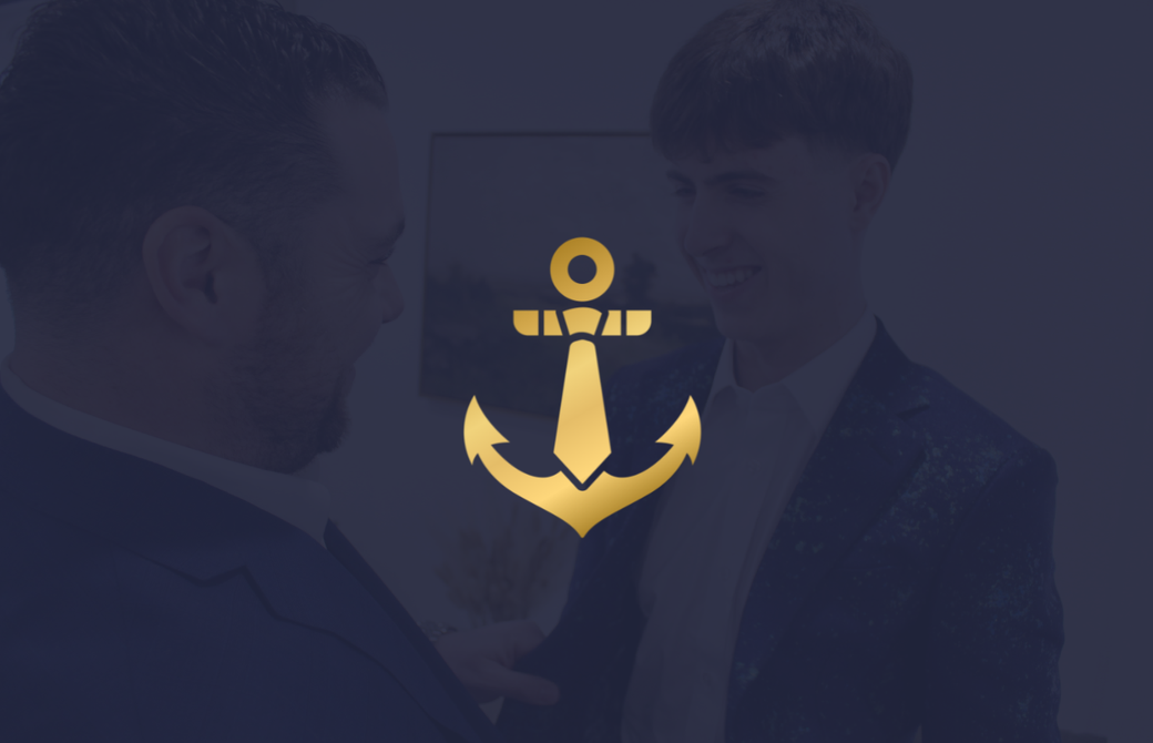 A man in a suit and tie is talking to another man with an anchor in the background.