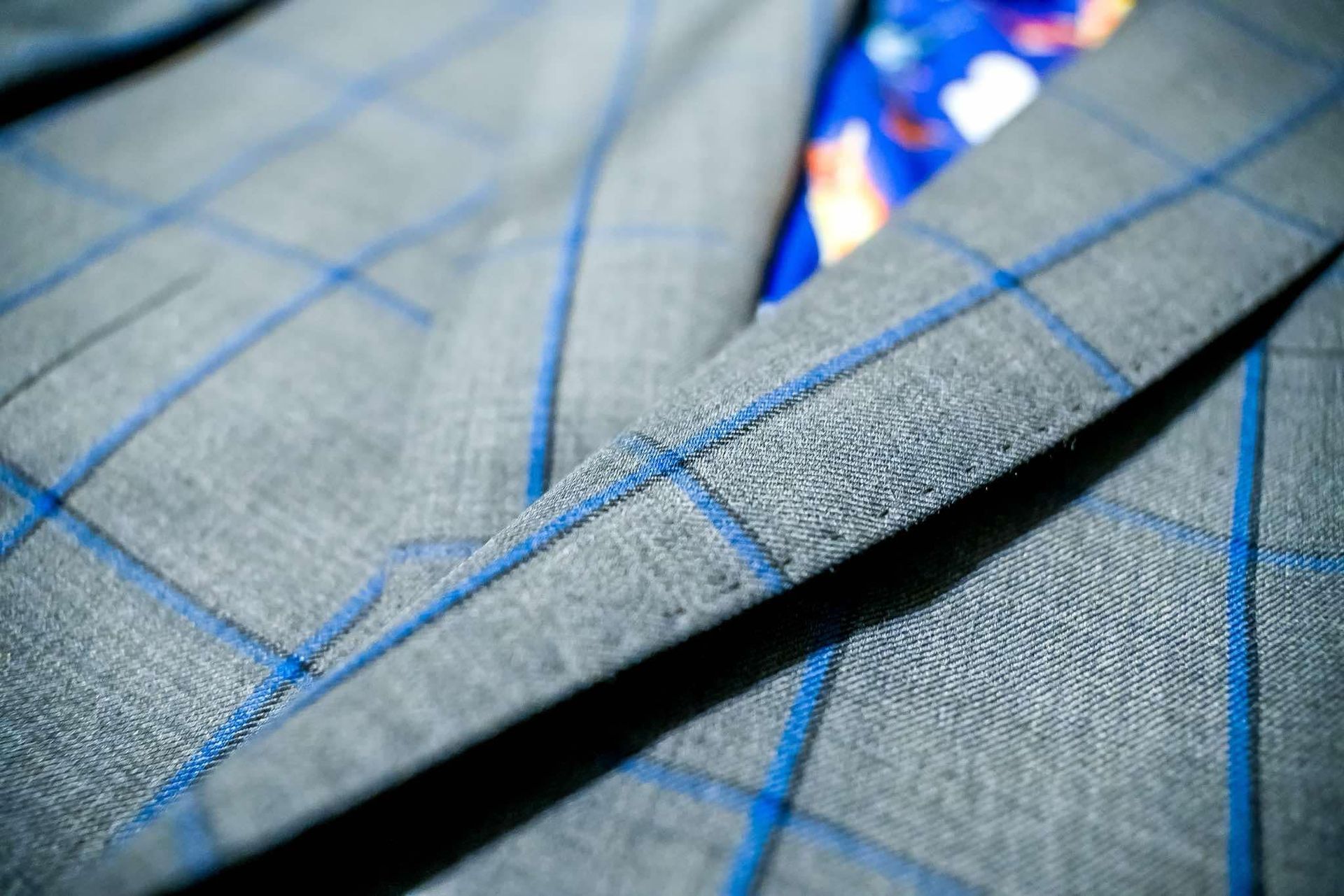 A close up of a gray suit jacket with blue stripes and a blue tie.