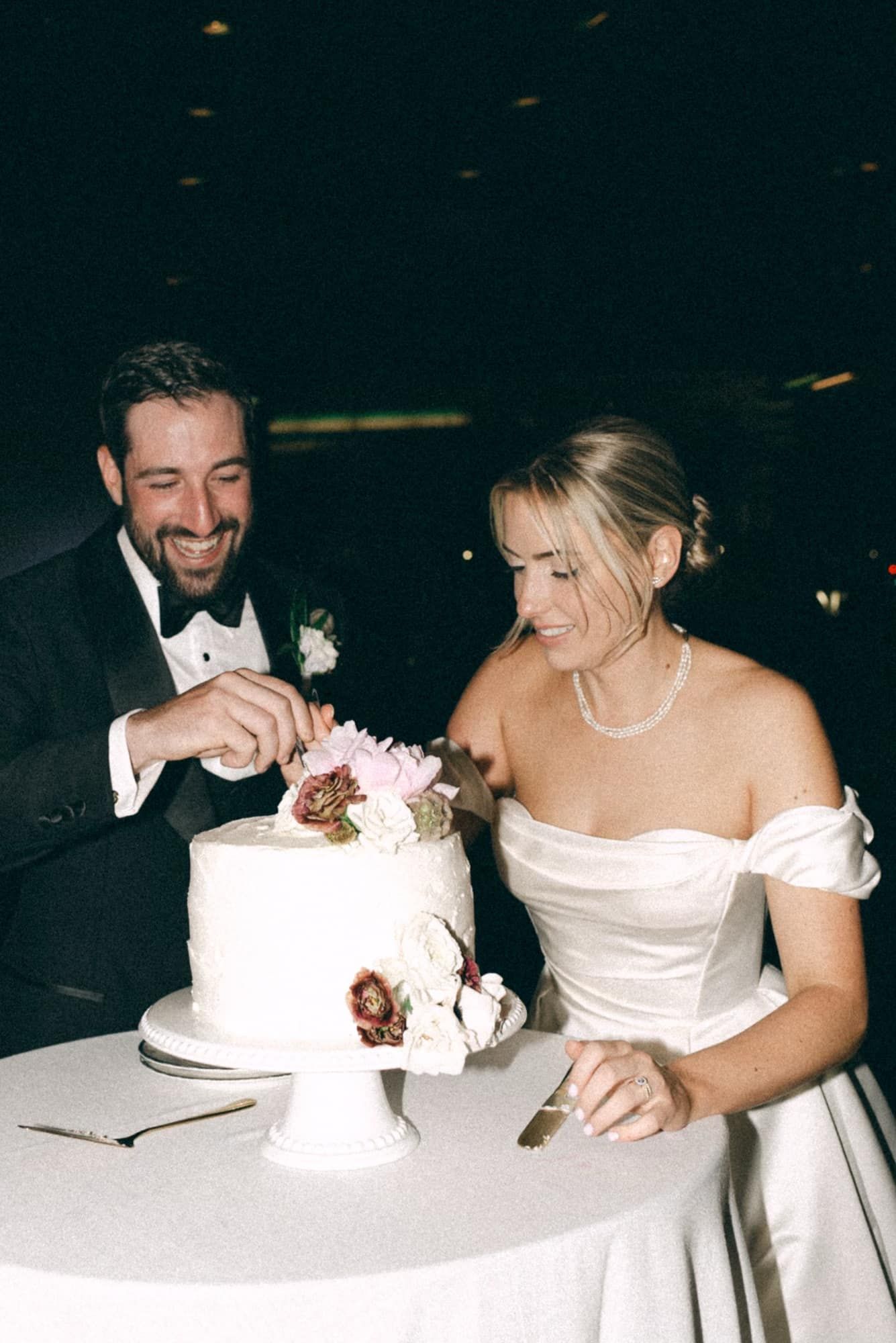 A bride and groom are cutting their wedding cake together