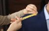A woman is measuring a man 's shoulder with a tape measure.