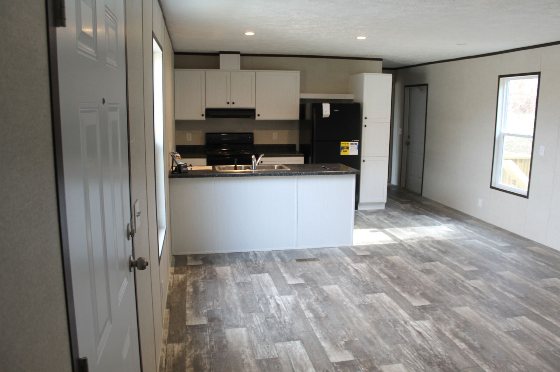 A living room with a kitchen and a refrigerator in a mobile home.
