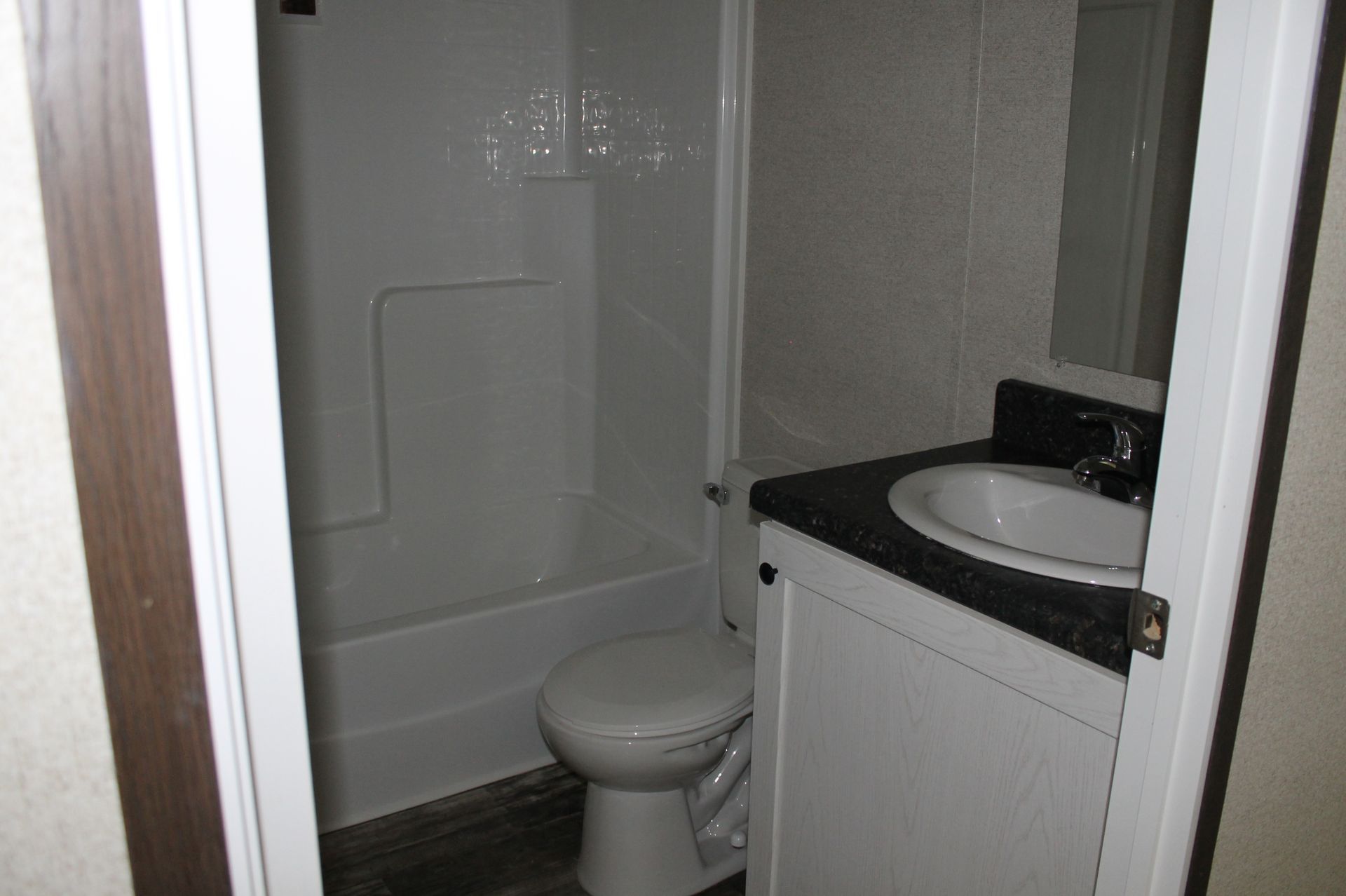 A bathroom with a toilet , sink and shower.