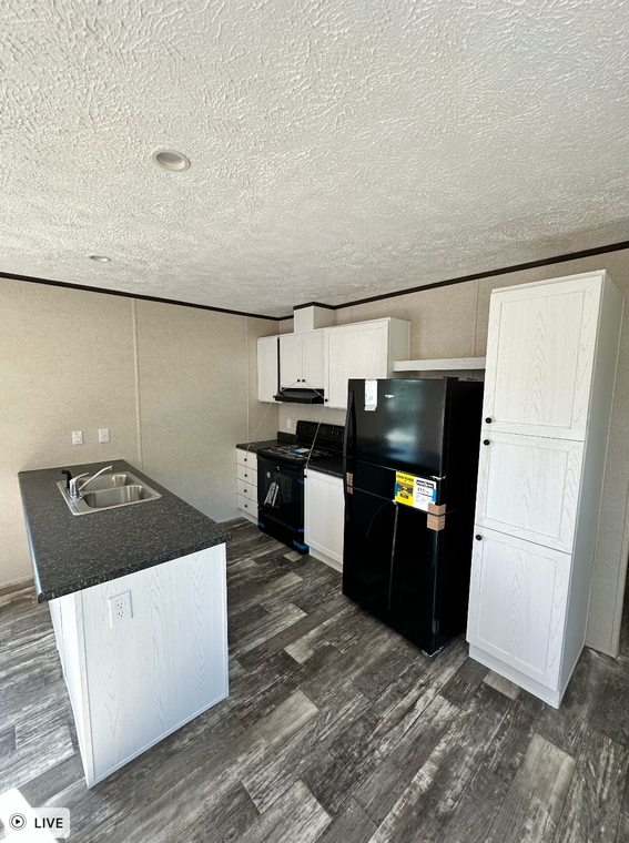 A kitchen with a refrigerator , stove , sink , and cabinets.