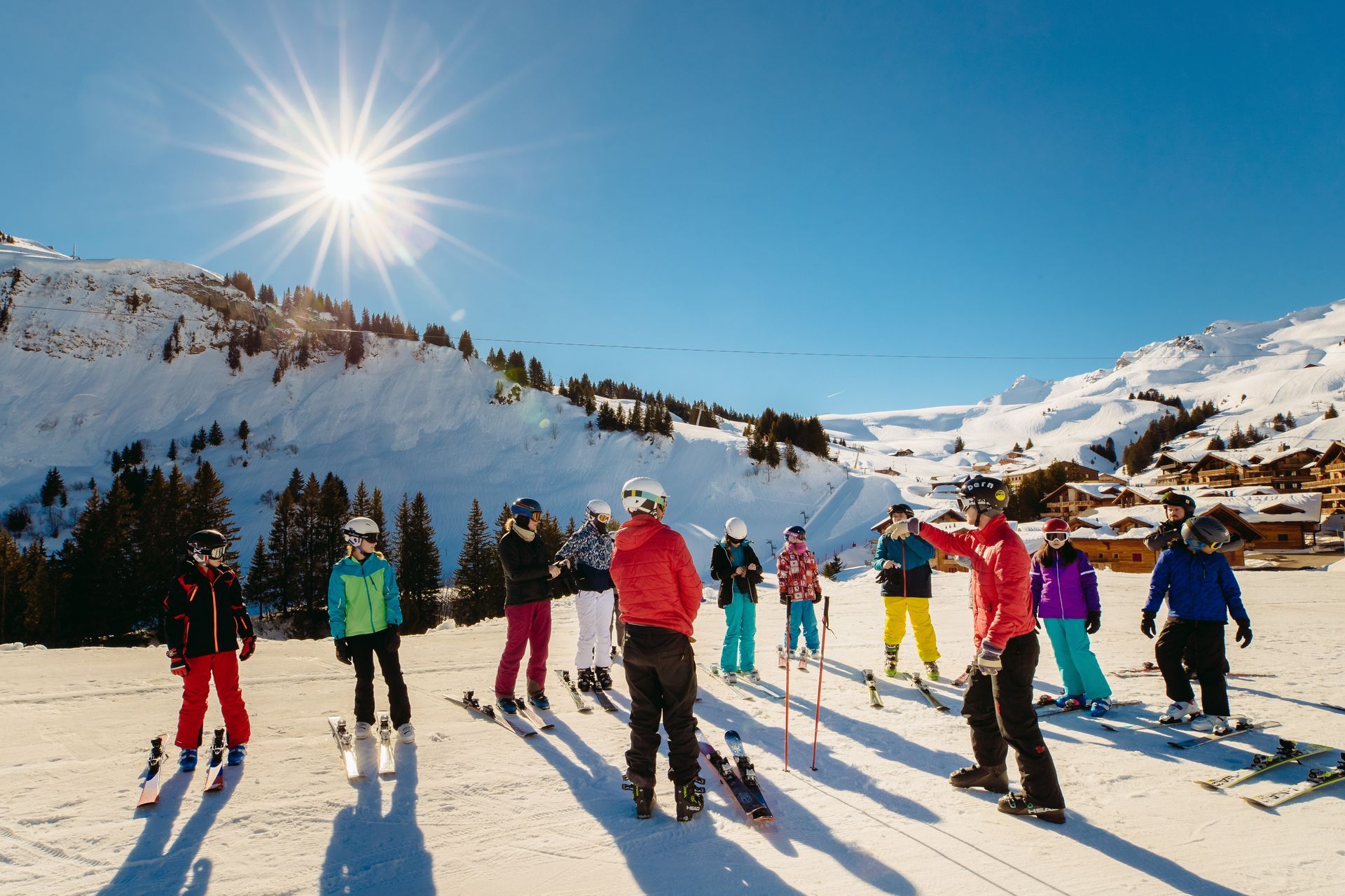 A group of skiers with a coach on a snow-covered mountain on a sunny day.