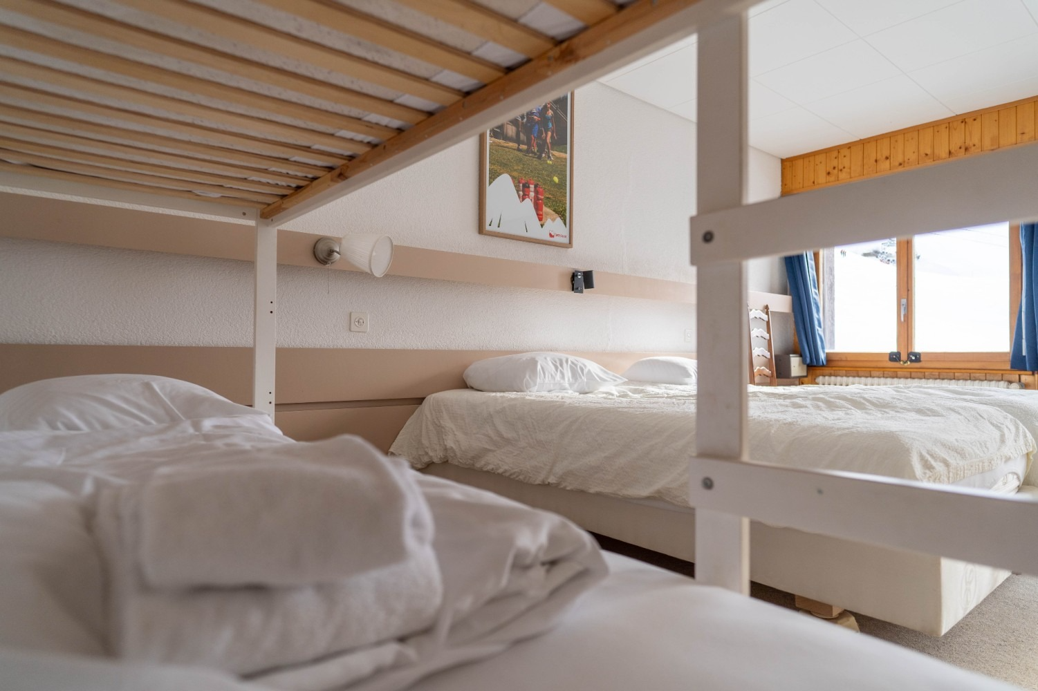 A brightly lit hotel room with bunk beds and two single beds.