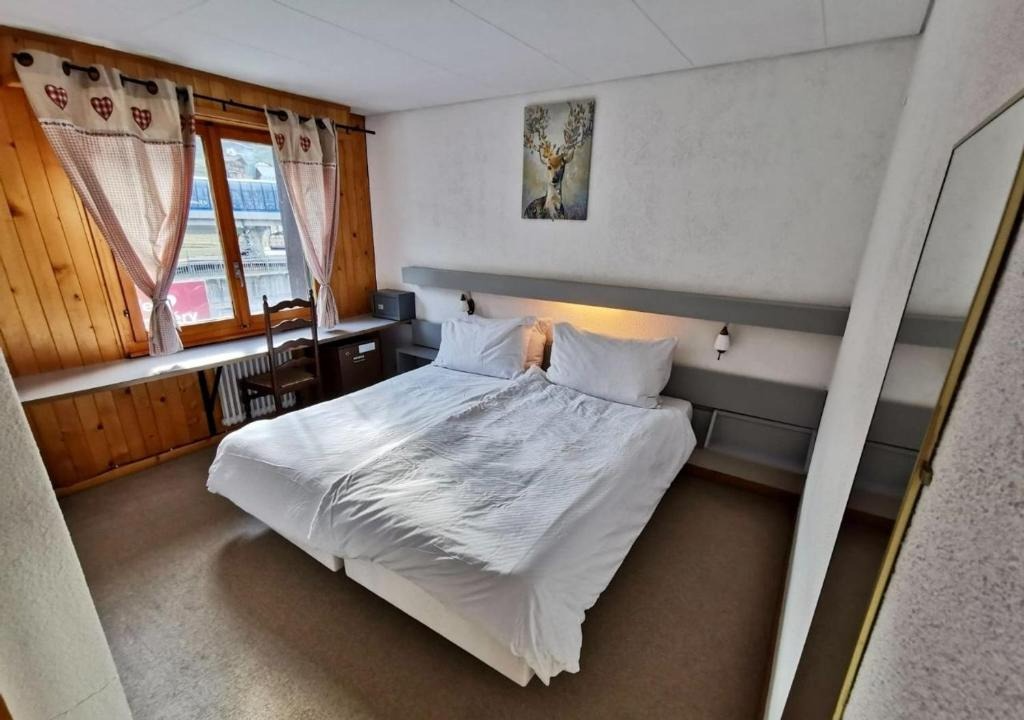 Bedroom with a double bed, window with curtains, desk, and a full-length mirror.