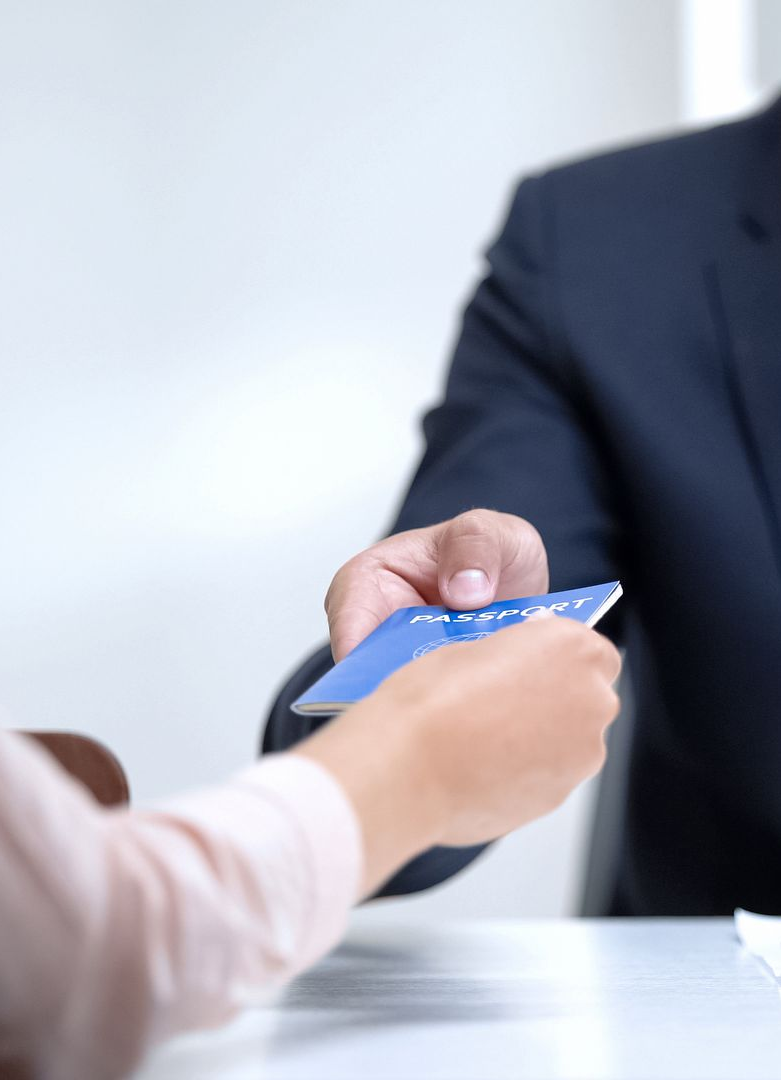 Person in suit handing blue passport to another person.