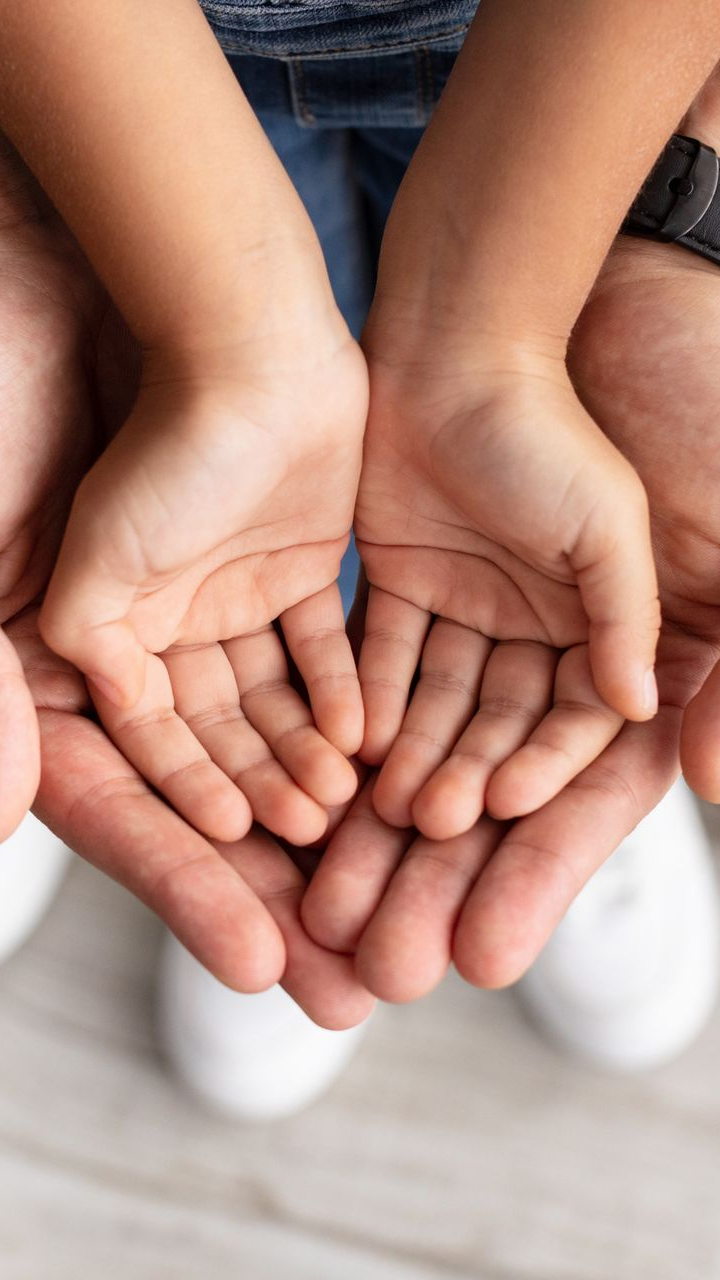an adult's hands and a child's open hands resting on top of each other