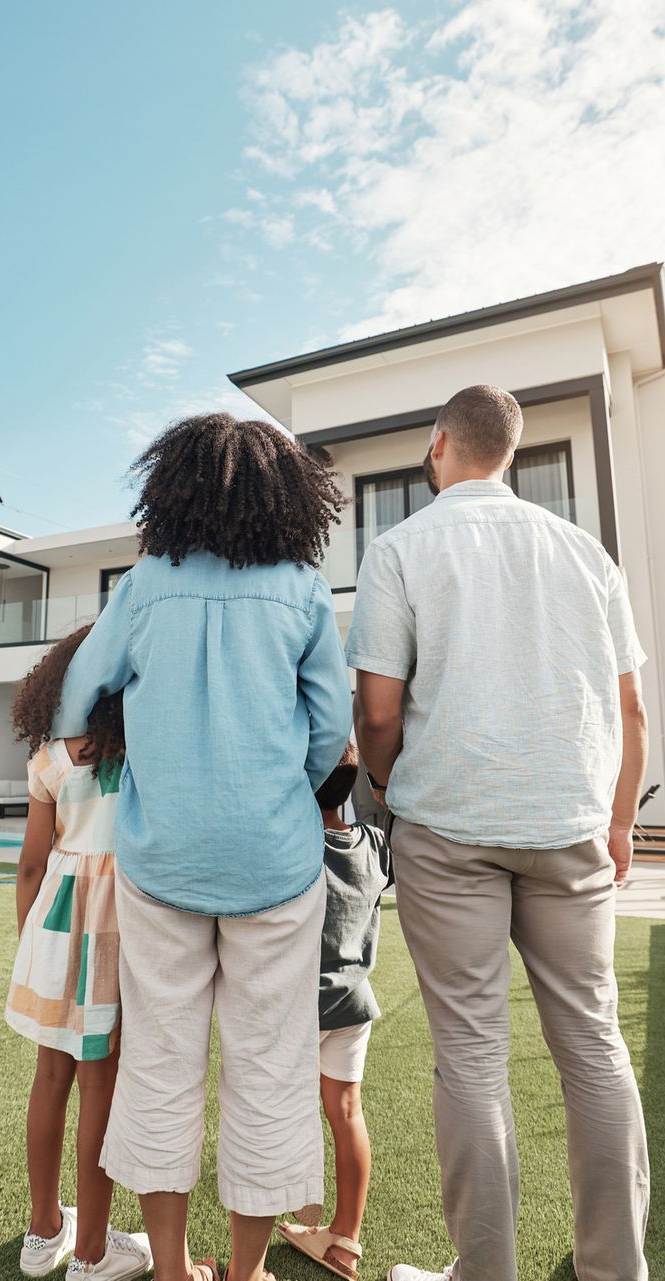 Family of four looking at a modern house on a sunny day.