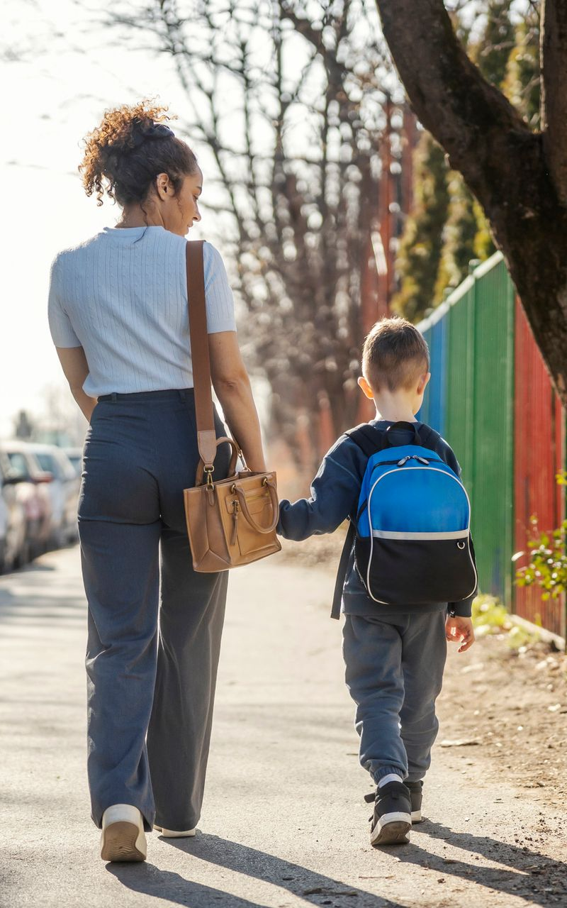 a mother and son walking on the sidewalk
