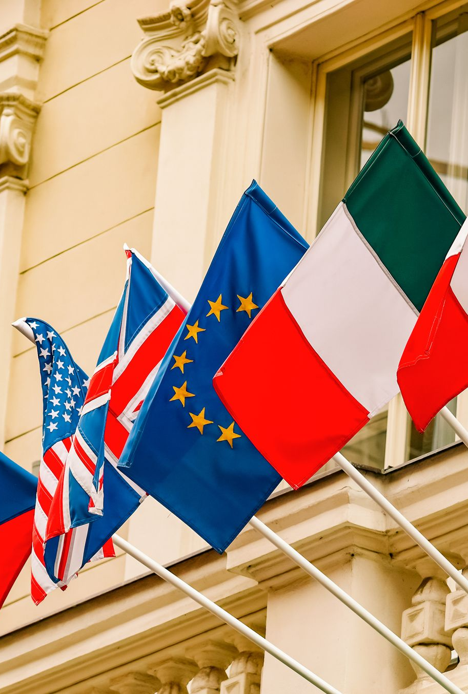 Flags of various nations and the EU waving from a building.