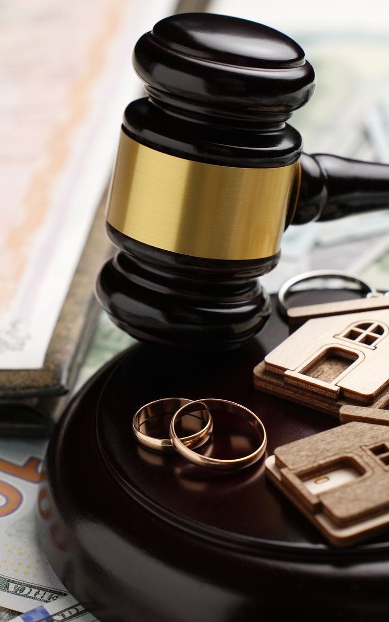 a gavel with house key chains and two wedding bands