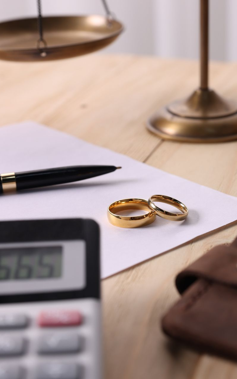 documents, a pen, a calculator, and wedding bands on a desk
