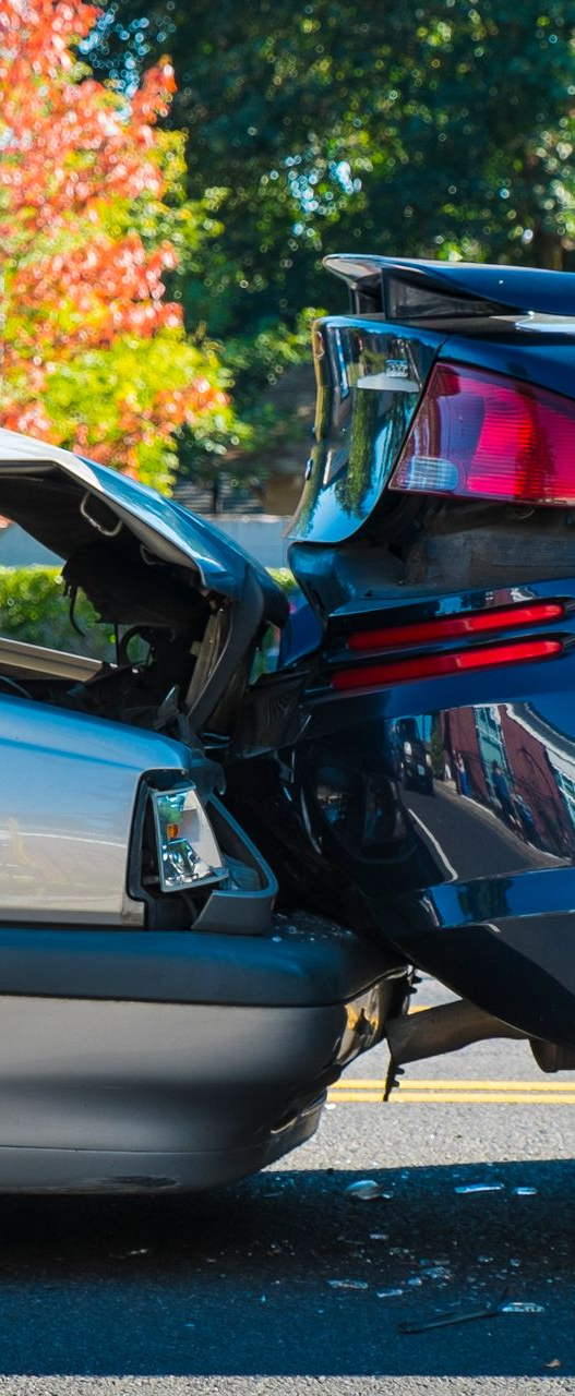 Two cars involved in a rear-end collision on a road, both damaged.