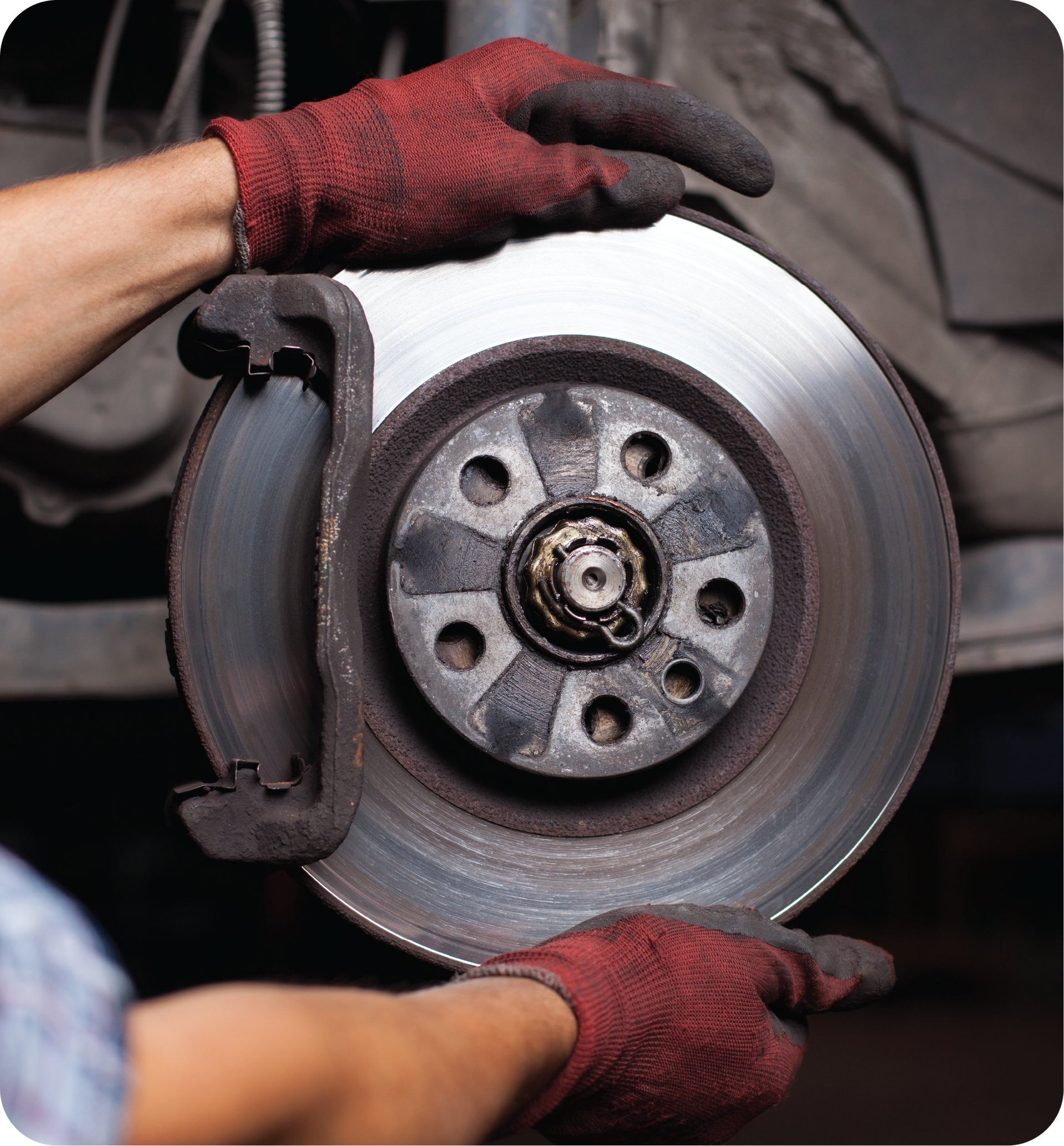 A person wearing red gloves is fixing a brake disc on a car.