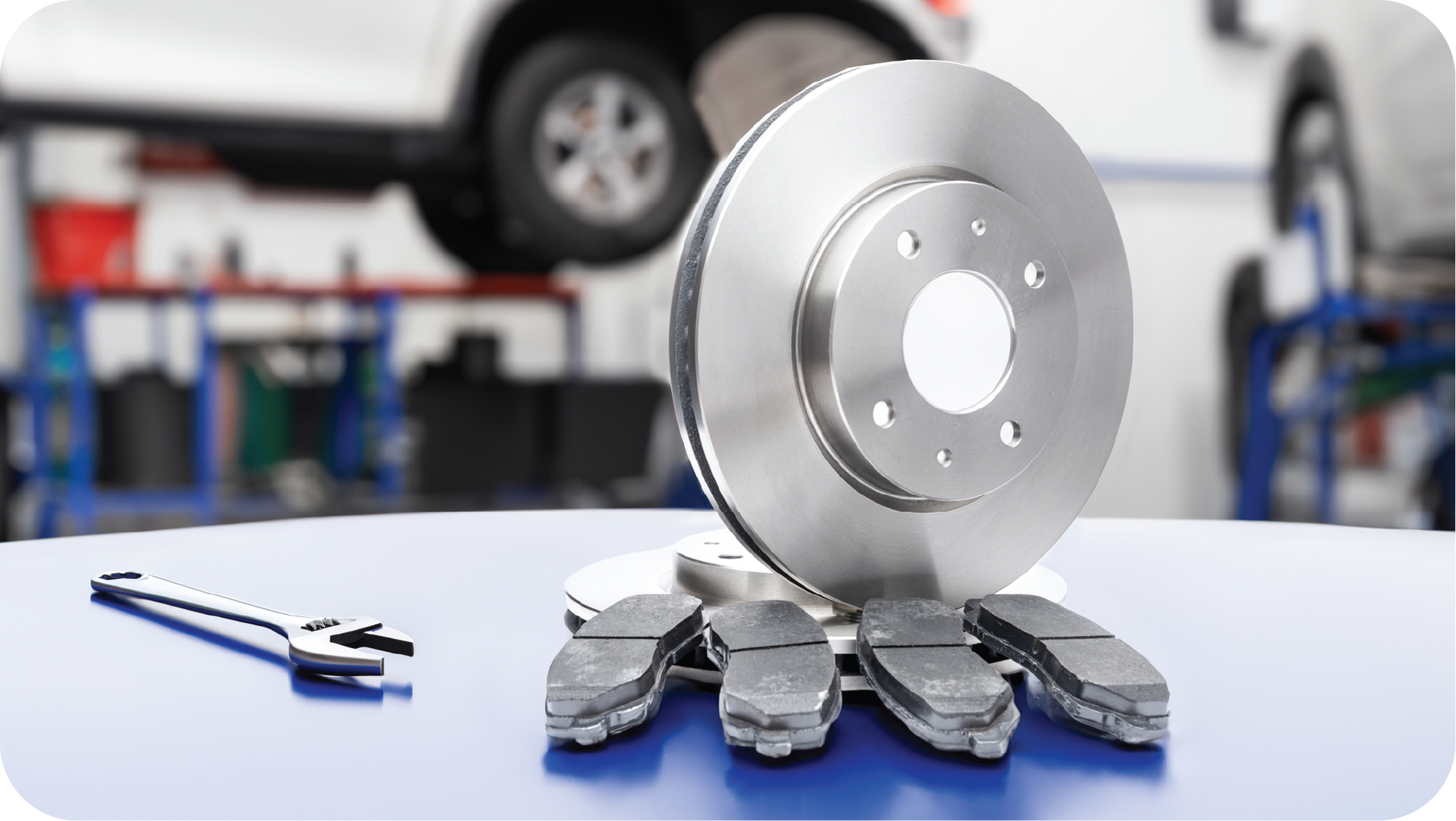 A brake disc and pads are sitting on a table in a garage.